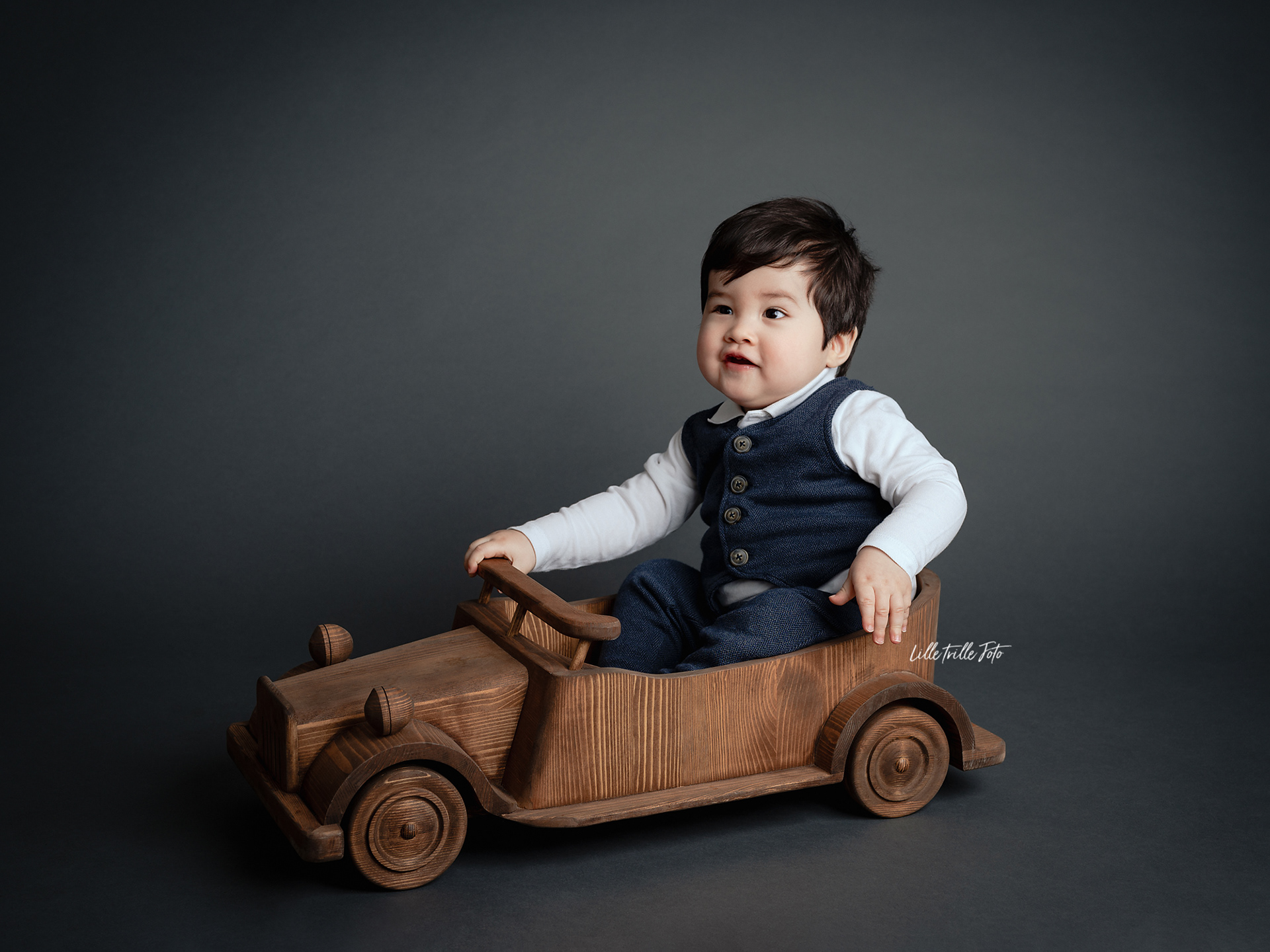 Barn elsker å kjøre i trebilen under babyfotografering, ettårsfotografering