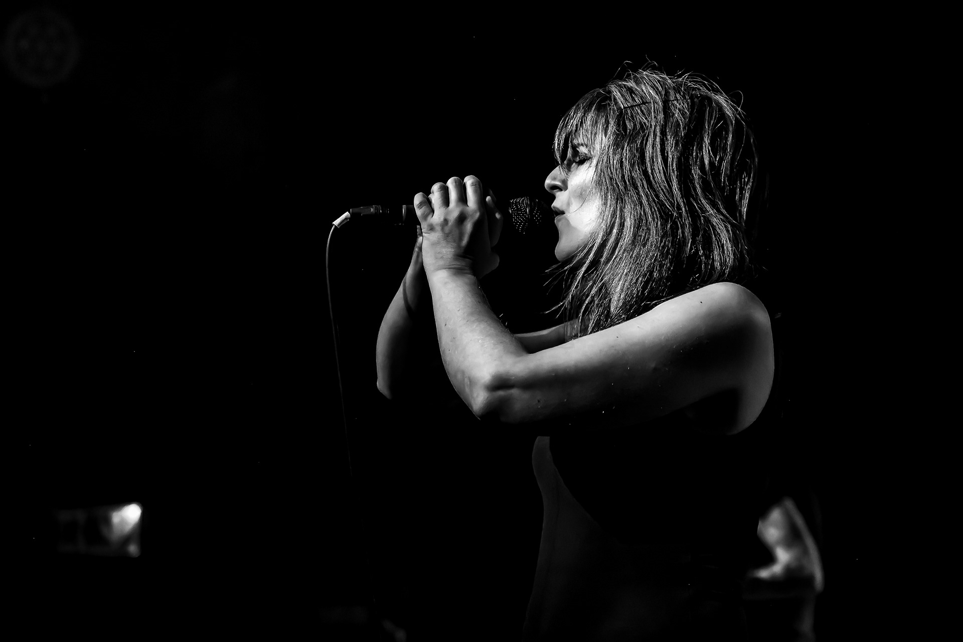Chanteuse en concert, portrait noir et blanc au micro sous les projecteurs 