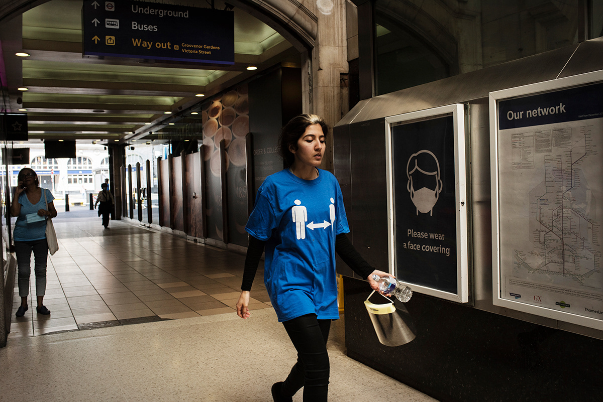 Members of staff wearing social distancing t-shirts to remind passengers to keep the 2 metres distance, London Victoria train station, Central London.
