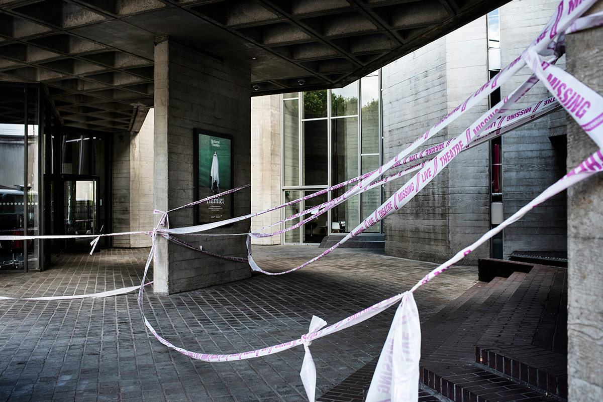The National Theatre wrapped in barrier tape reading “Missing Live Theatre”, SouthBank, London.Theatre buildings around the country closed due the coronavirus crisis have been wrapped with messages of hope as part of a project by stage designers group Scene Change.At the beginning of July, due to the changes in the government Job Retention Scheme, National Theatre made redundancy for 400 of its casual staff, including its 250-person front of house and 150-person backstage teams. After a seven month lockdown, the National Theatre has announced to reopen in late October with the one-person play Death of England.