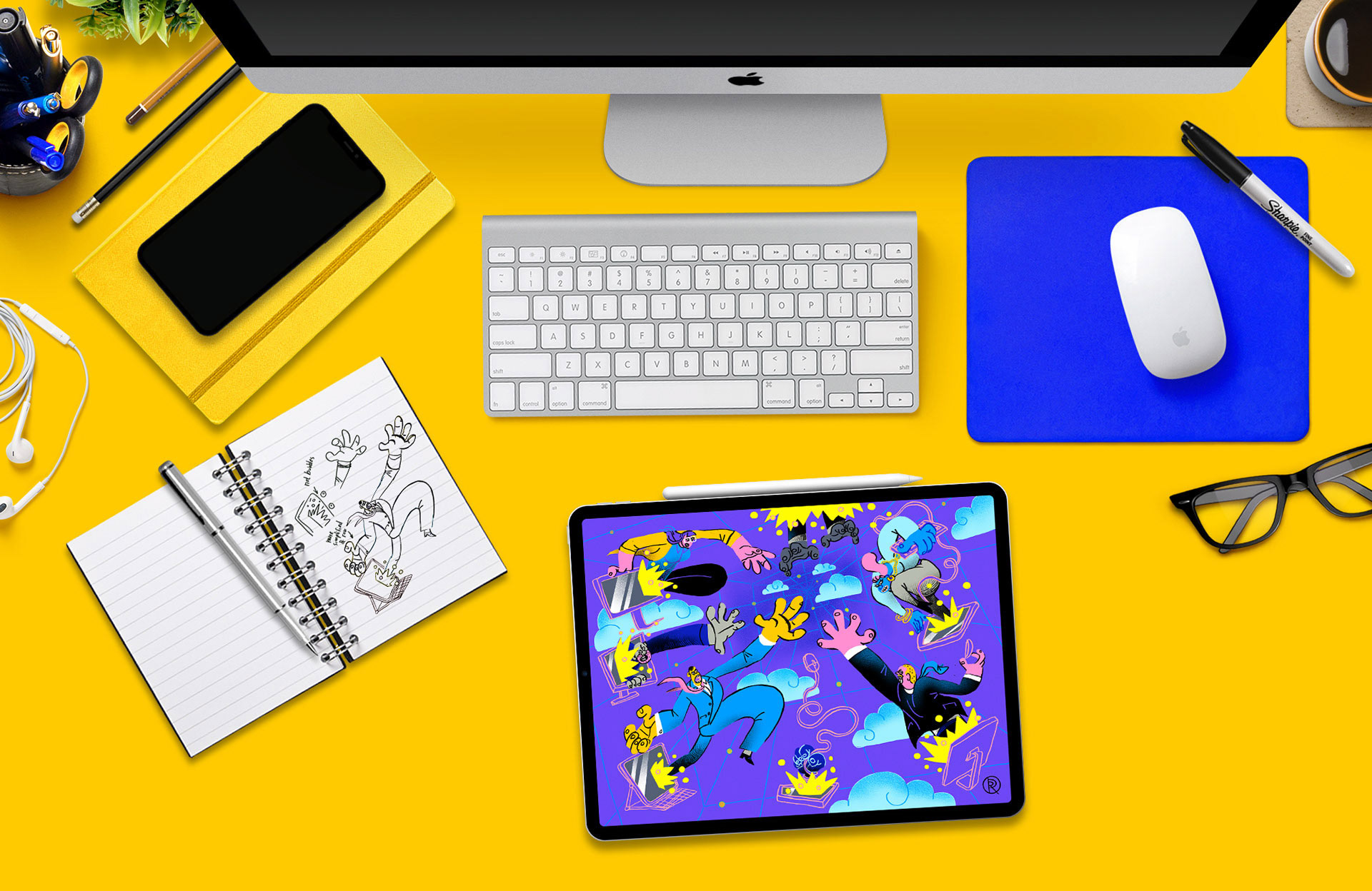 An artists' yellow creative desk workspace viewed from above showing a flurry of creativity