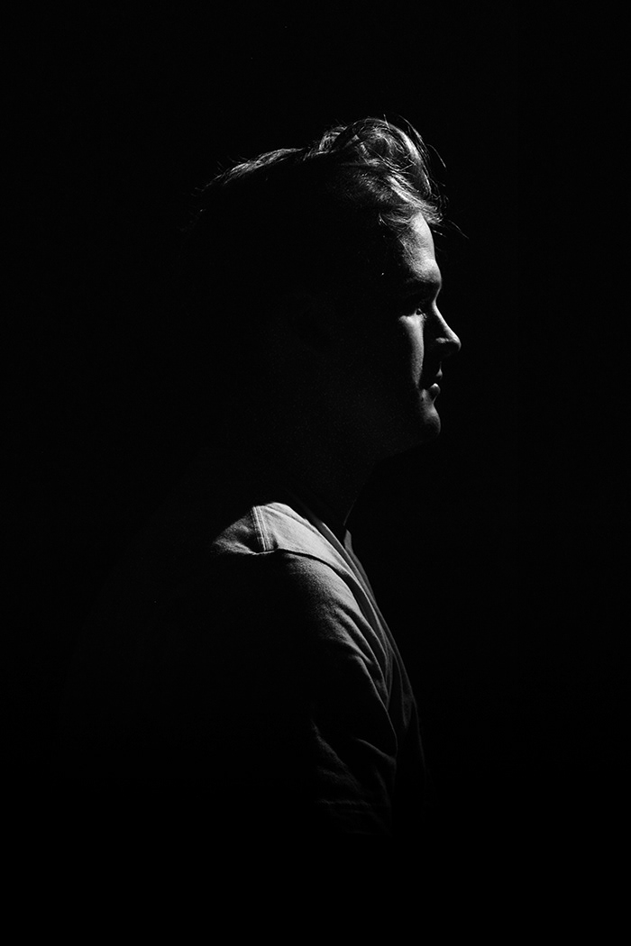 Profile view of a man, barely visible though the surrounding blackness.