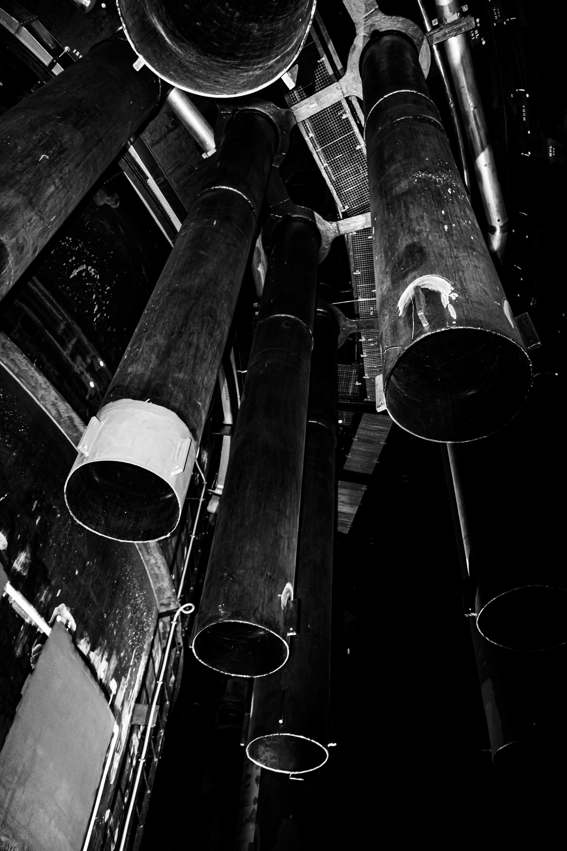 Black and white photograph of large industrial pipes in a nuclear facility, dramatic perspective and strong contrast.