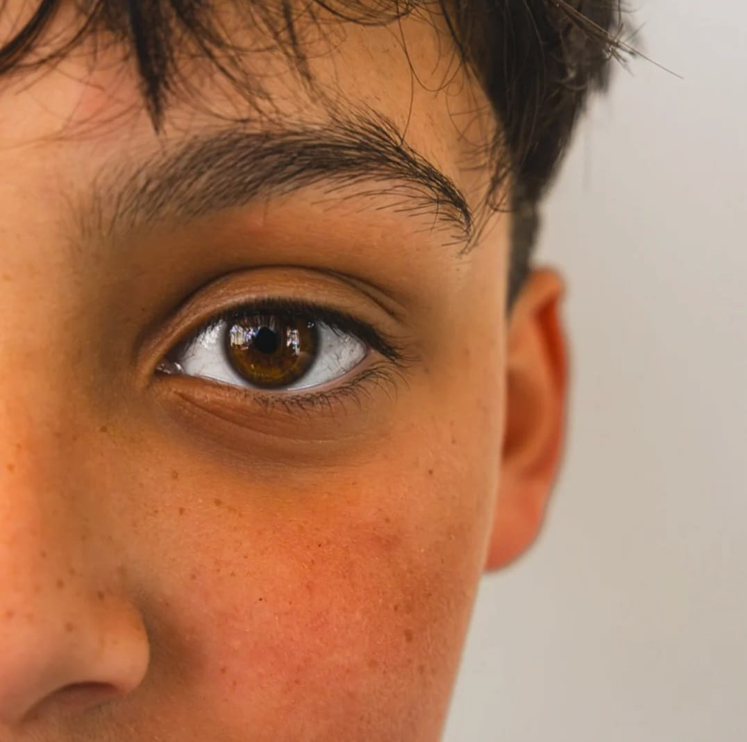 El primer plano del rostro de un niño, revelando su ojo derecho, la ceja, las pecas y una tez color canela.
