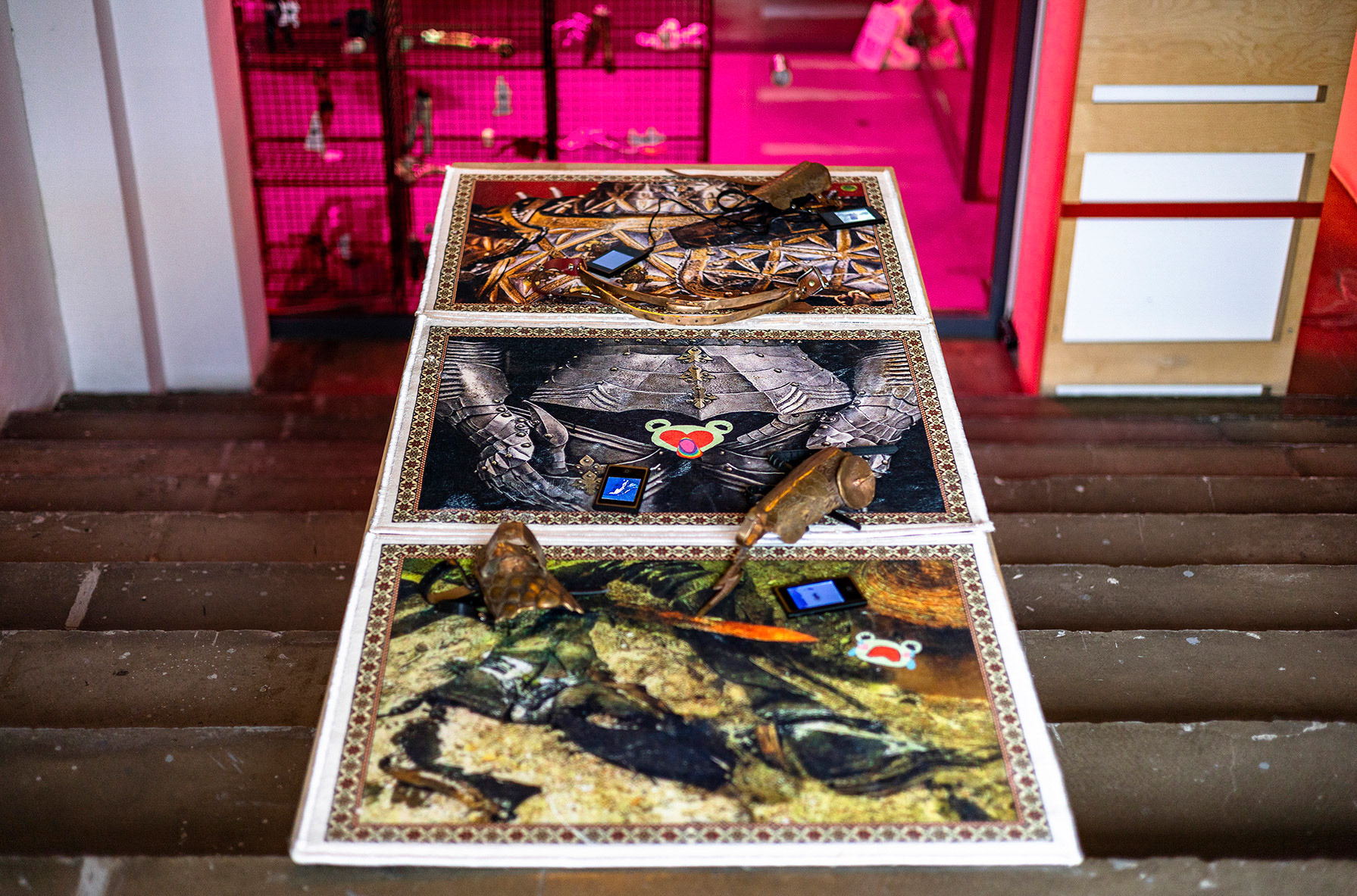 Monika Czyżyk, Frogo Knitix 1-2-3, 2022, Digital print on a carpet, selection of AVI videos from BOdyssey archives, mp4 players, bronze armor with leather mounts, 180 x 80 cm
