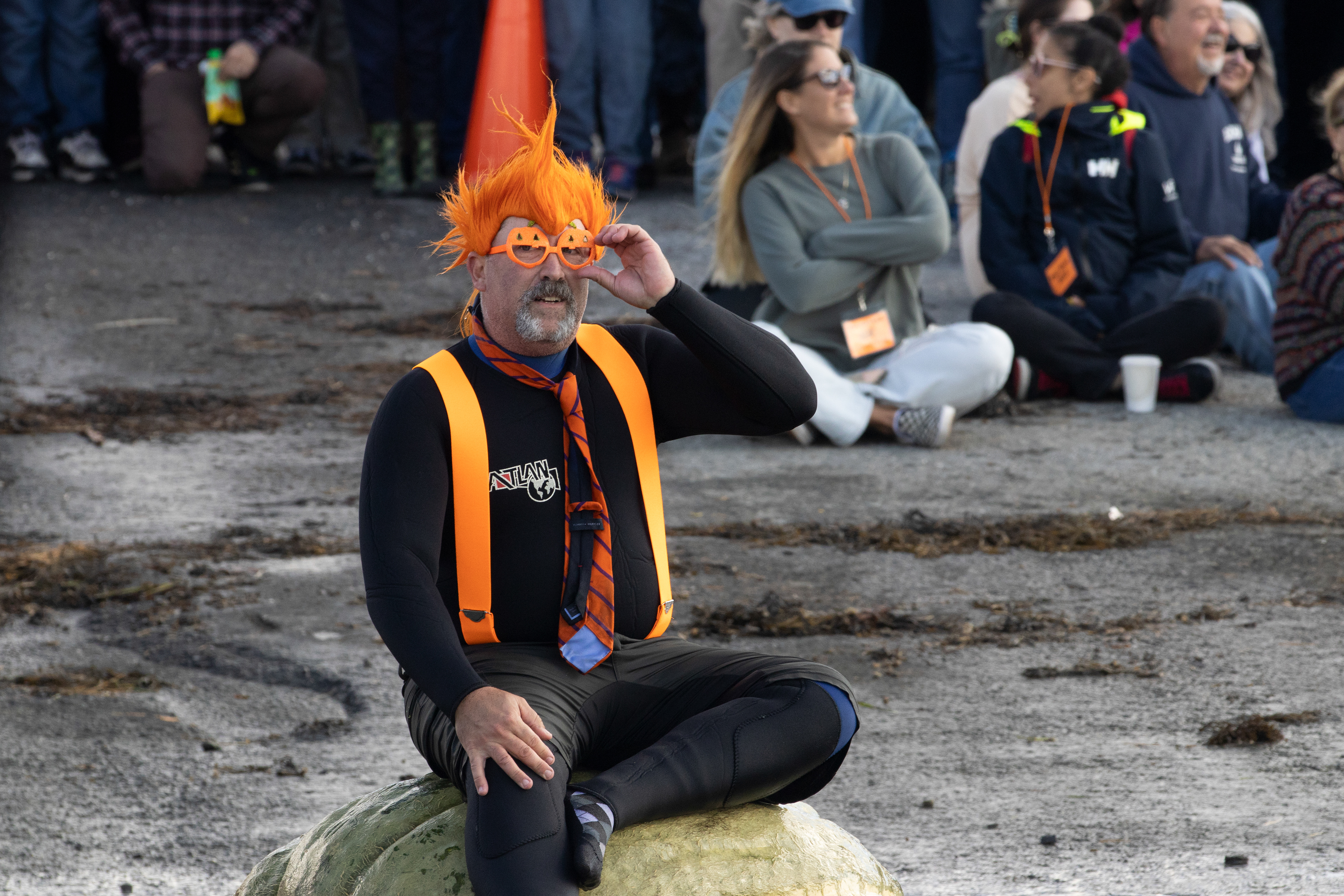 One of the paddlers sits on an overturned pumpkin boat to spectate the race at the Damariscotta Pumpkinfest Regatta on Oct. 9, 2023. The regatta is a tradition in the coastal Maine town where people come from all over the country to race boats made out of giant pumpkins.