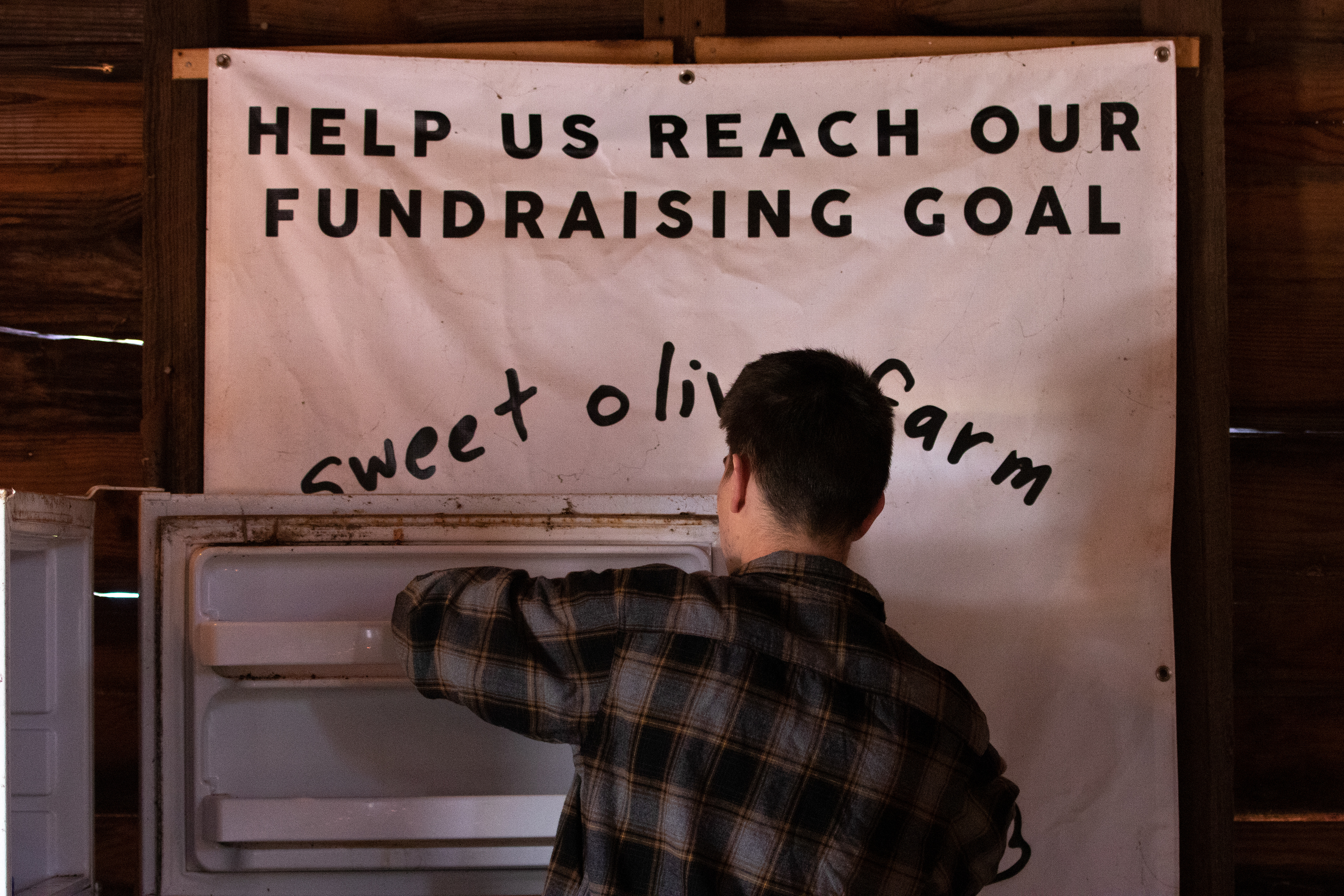 A volunteer cleans out the refrigerator in the barn at Sweet Olive Farm Animal Rescue on March 20, 2022 in Winterville, Georgia. Sweet Olive relies on volunteer work every day of the week to keep the farm running, especially since they can’t afford to hire permanent farmhands. They require $15,000 a month just to keep running, so they make their money through events and fundraising.