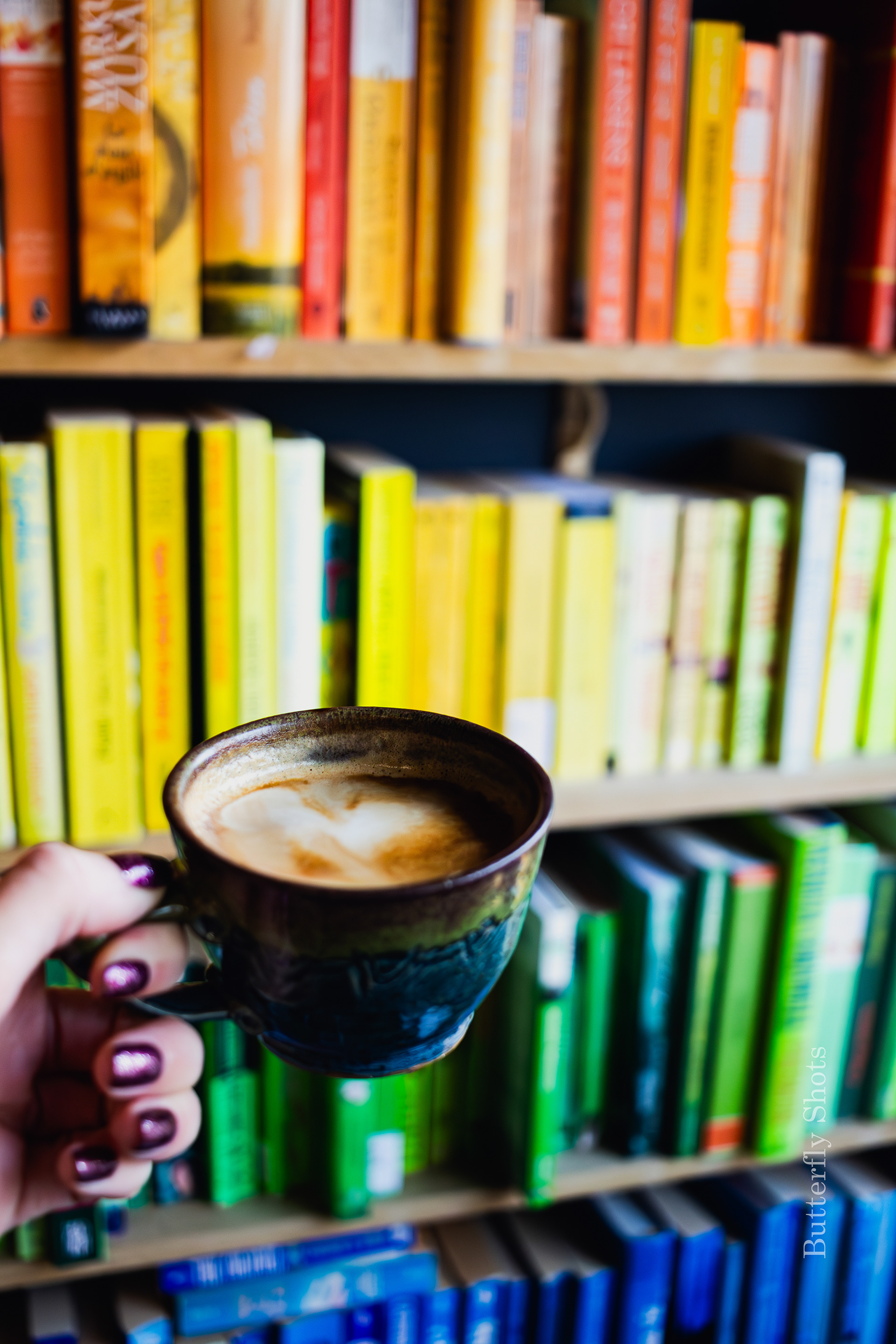 Product photography of a cortado coffee in front of rainbow bookshelve