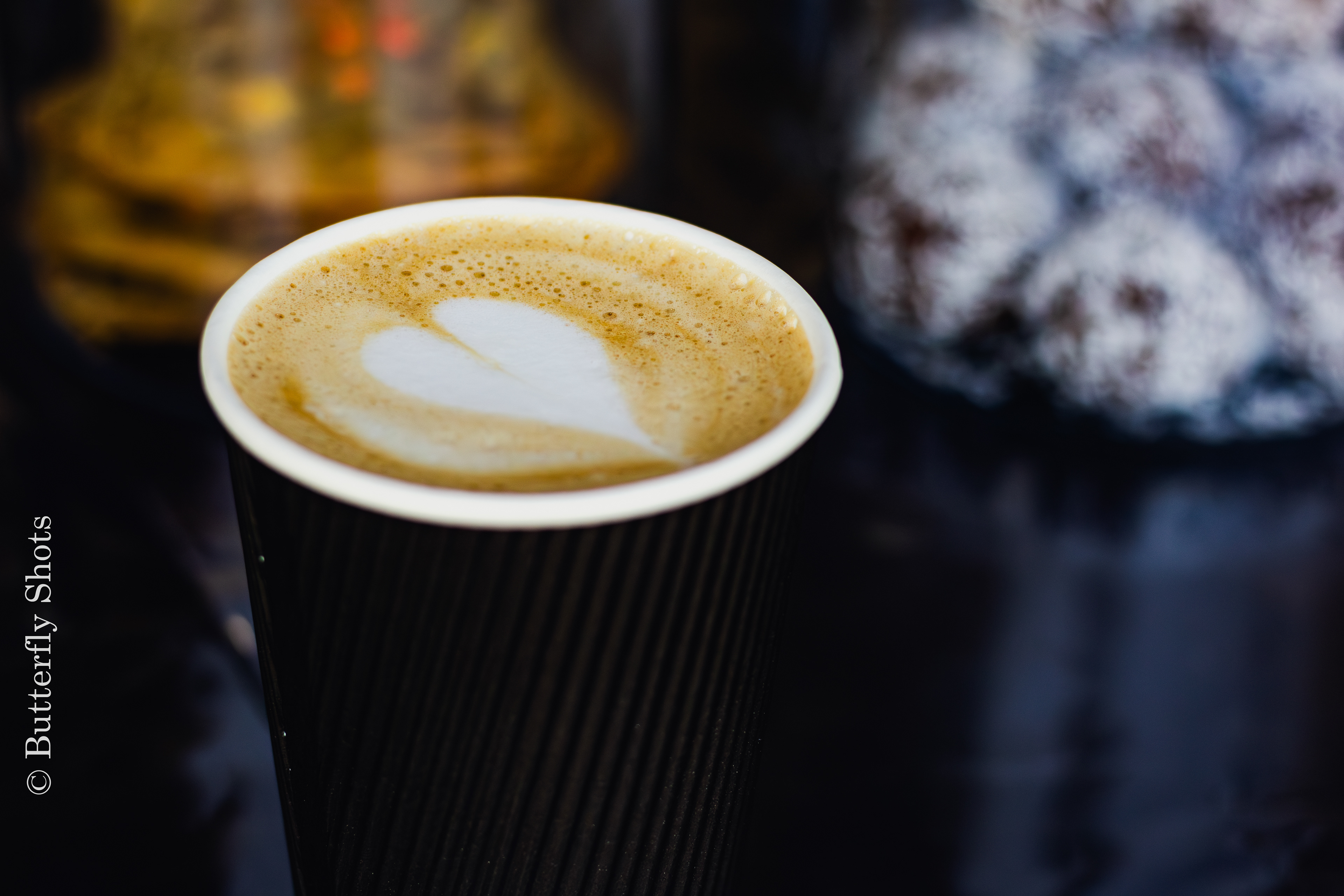 Product photography of a latte coffee in front of snacks