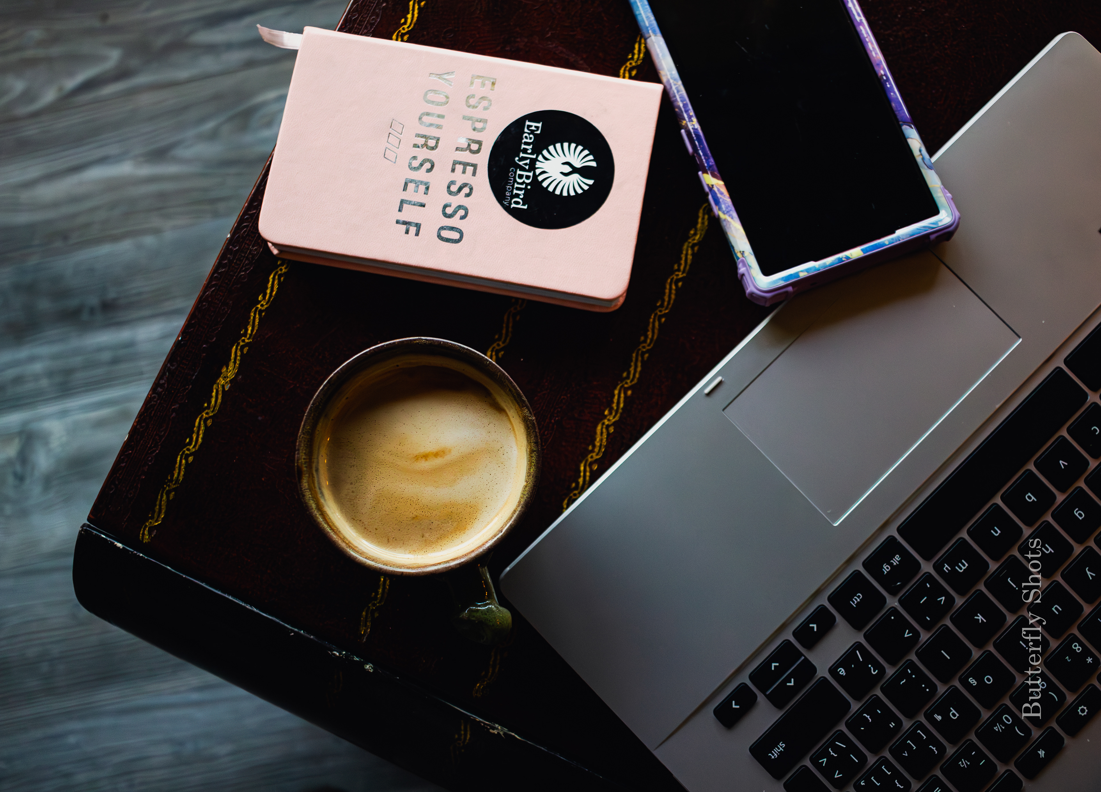 Product branding photography of a cortado coffee with computer, phone and notebook