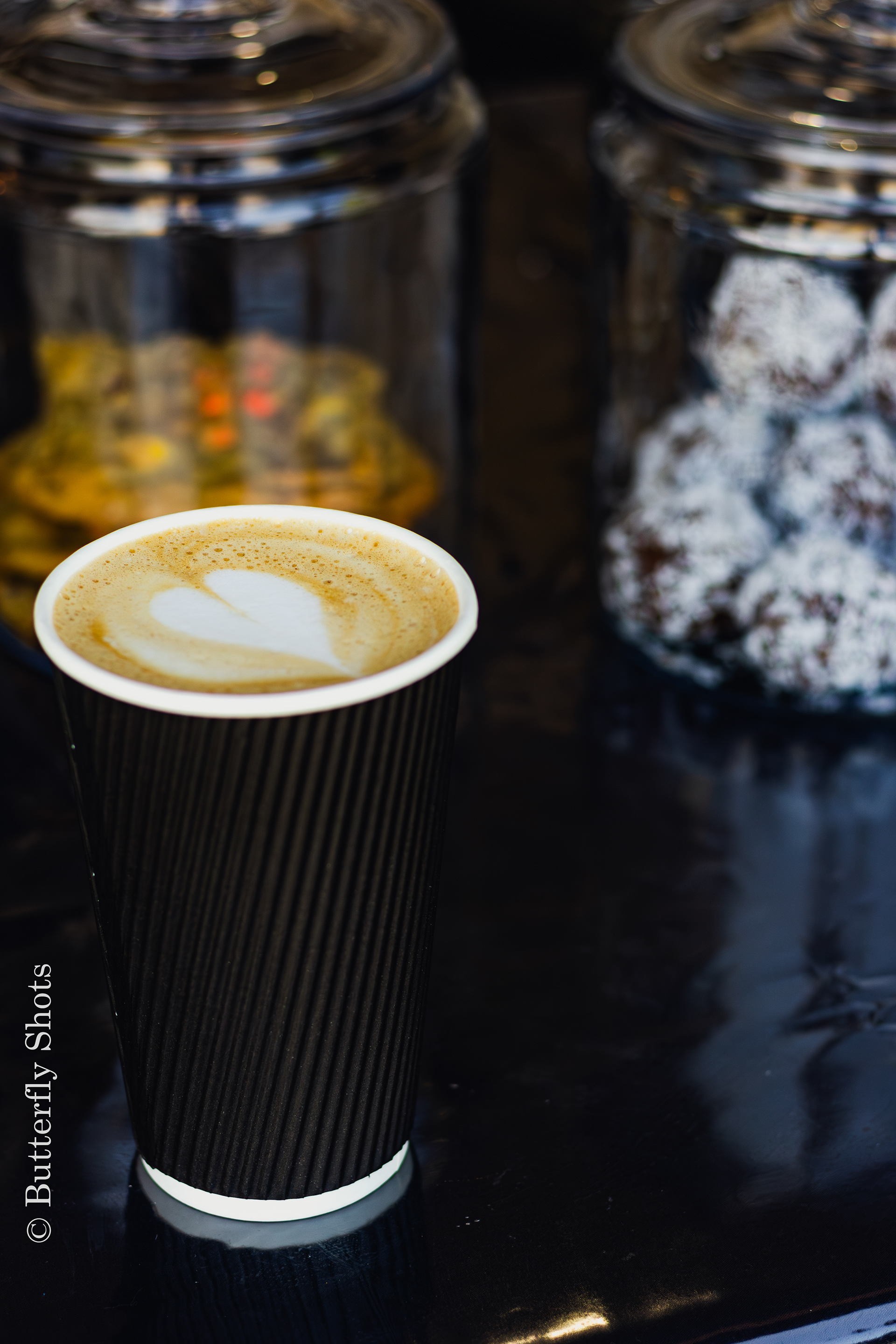 Product photography of a latte coffee in front of snacks