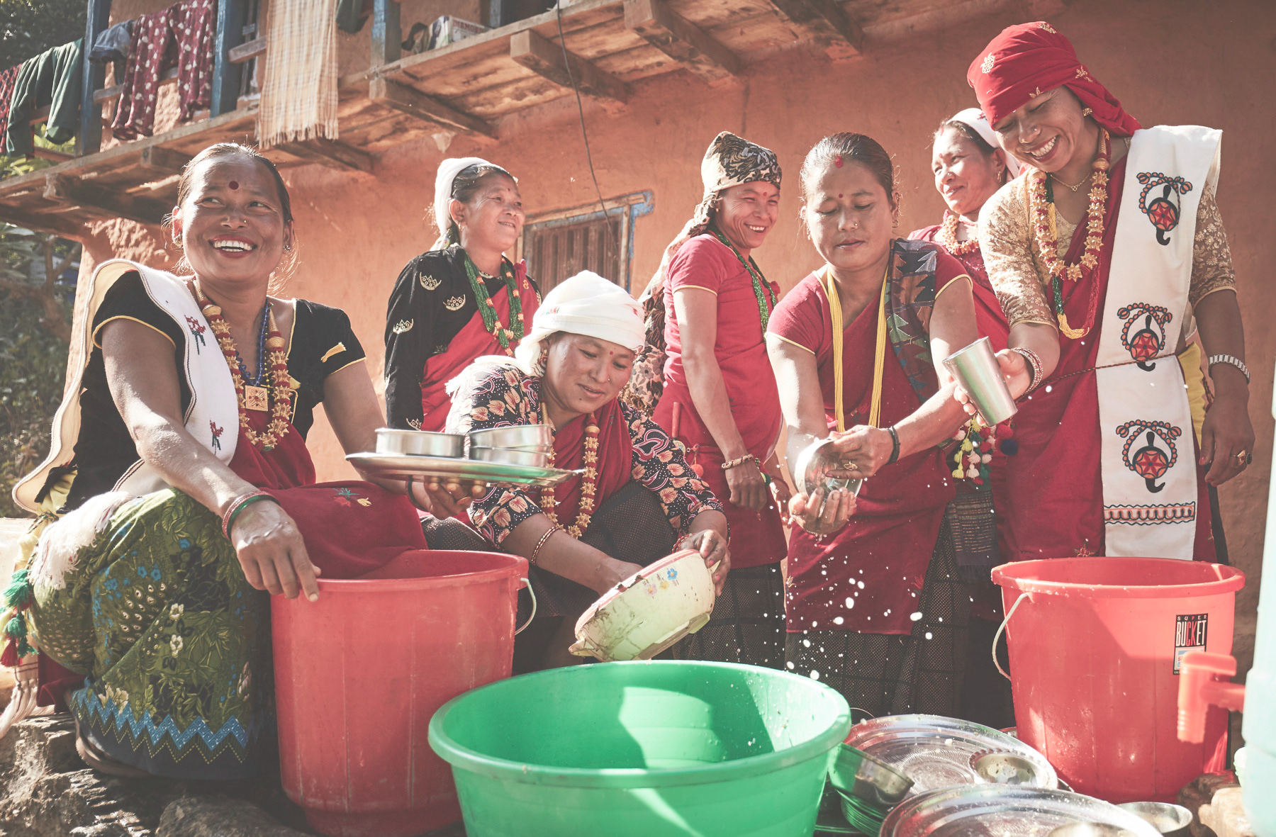 Nepali women washing dishes and laughing. Photo by David Walter