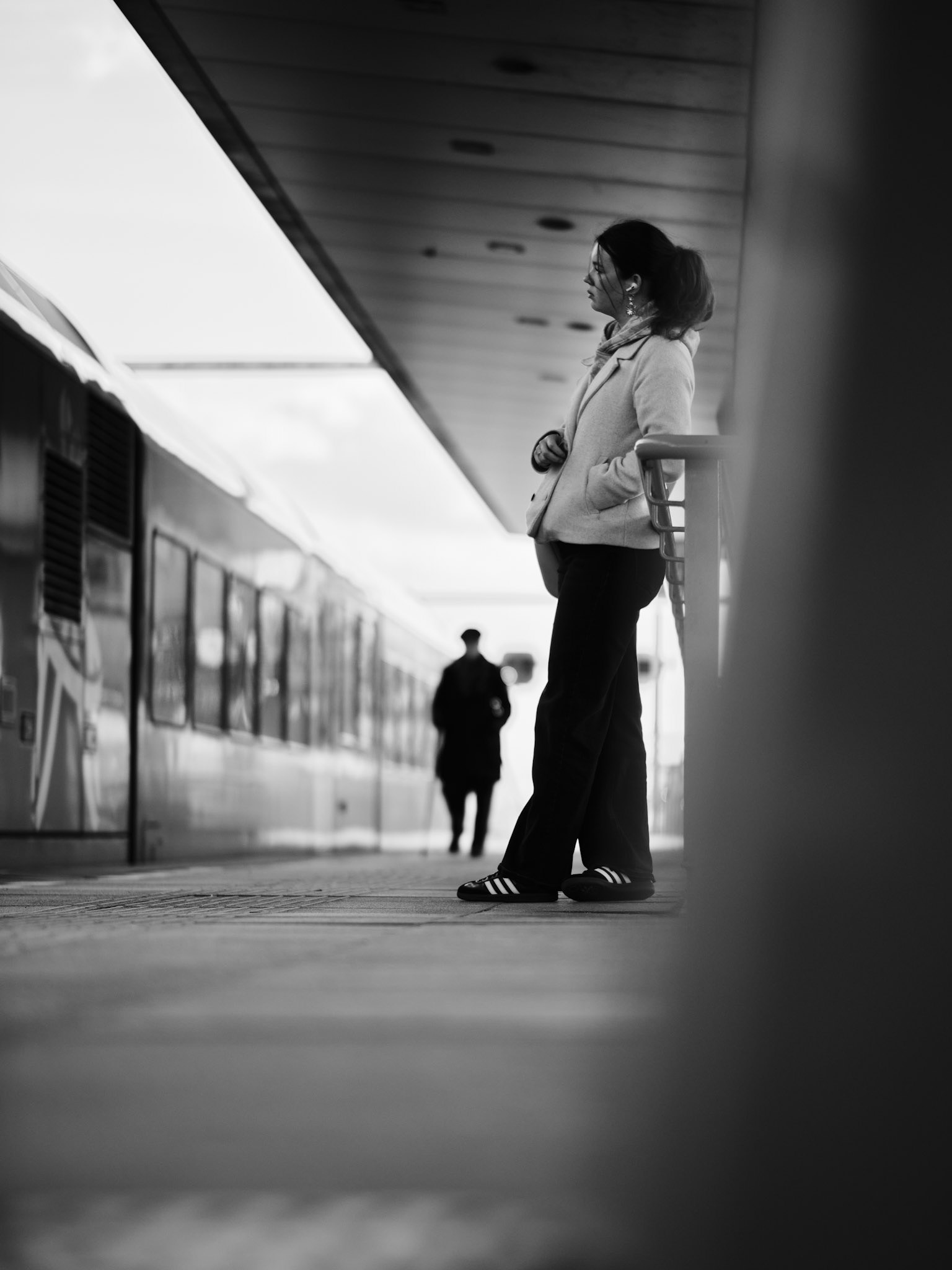 Wachtende vrouw, stokman kadert treinverhaal.