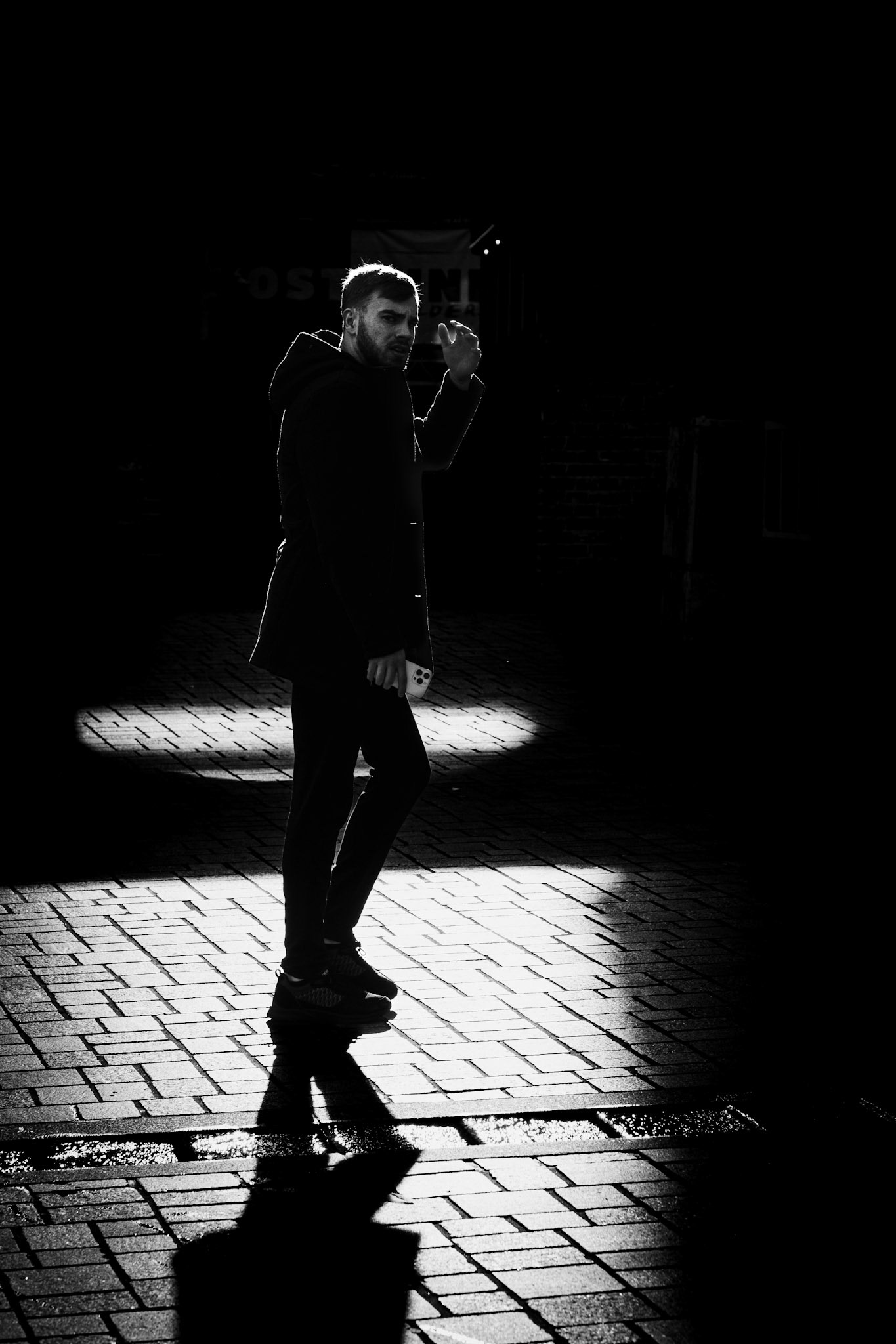 Hij draait zich om, oog in oog met de lens, straatlicht verraadt hem.