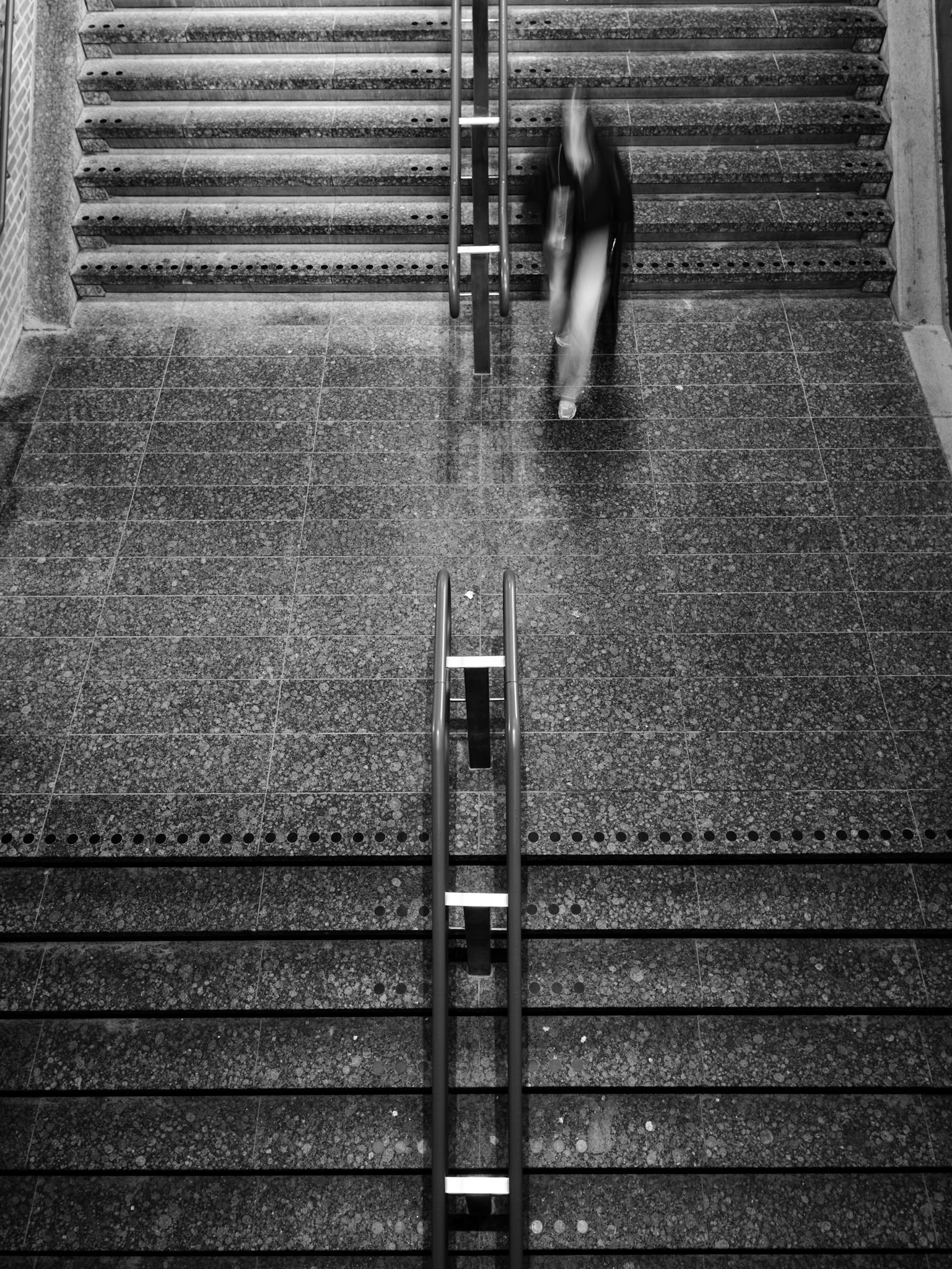 Gehaaste reiziger snelt trap af op station.