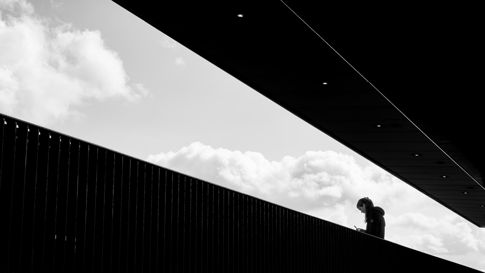 Zwart-wit uitzicht: figuur tussen wolken en staal.