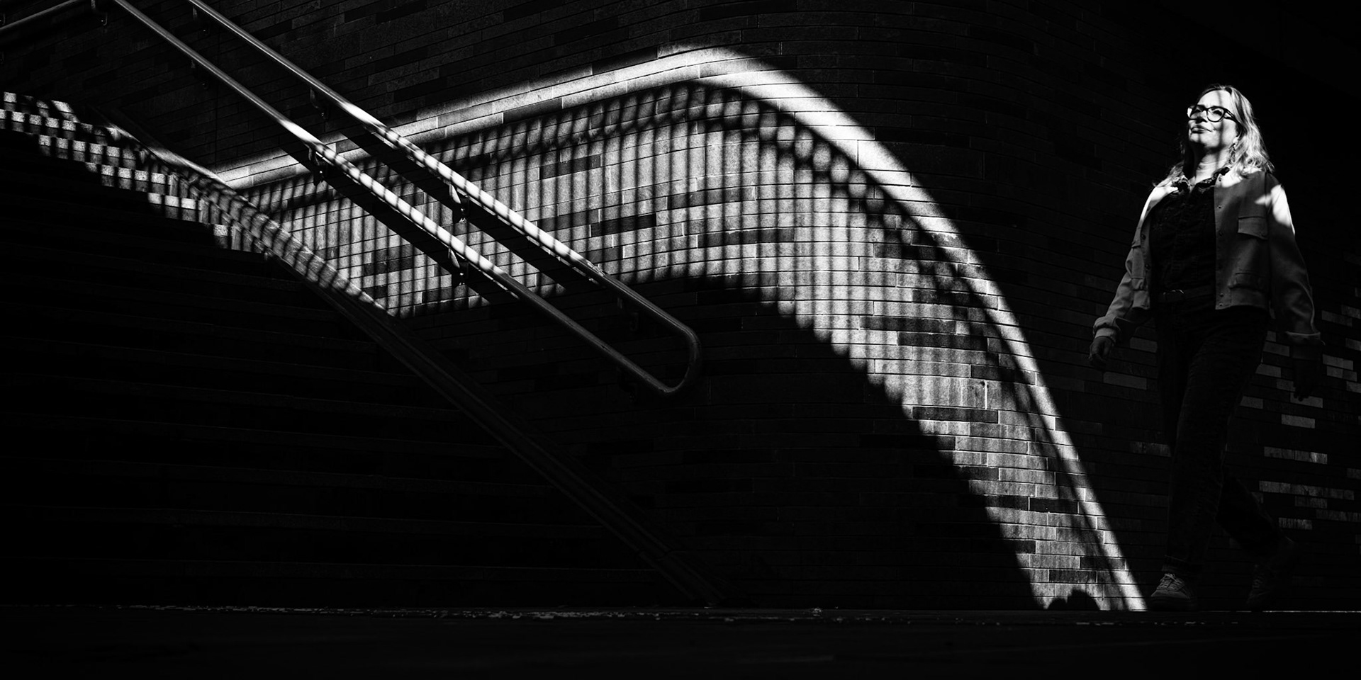 Vrouw passeert licht en schaduwspel op trap Europapark.