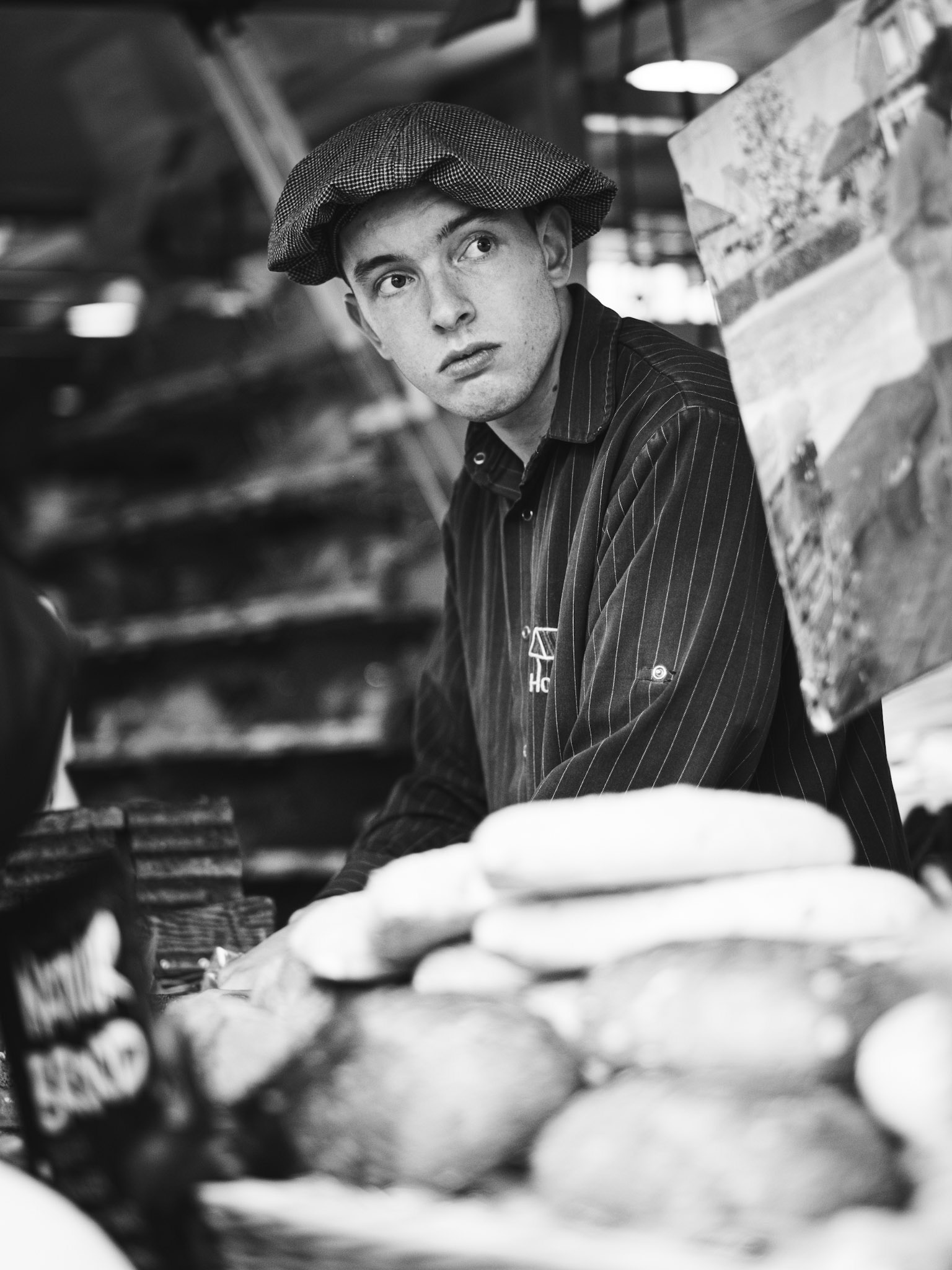 Verse broden en directe blik – straatportret bakker met pet, urban daily life in Winschoten stijl.