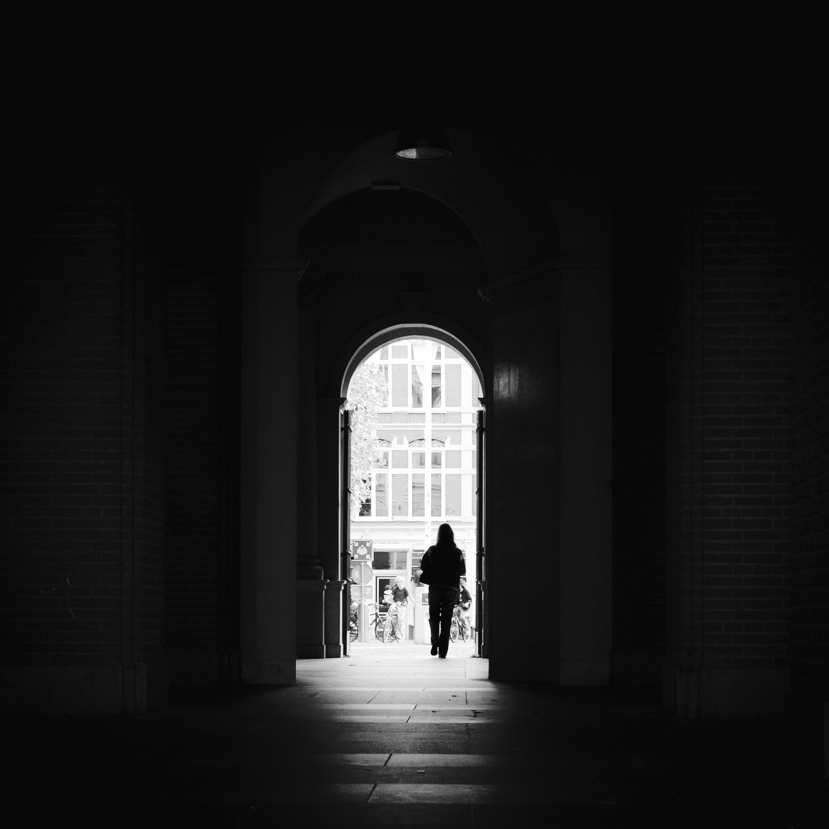 Zwart-wit doorgang: figuur in lichtstraal architectuur.