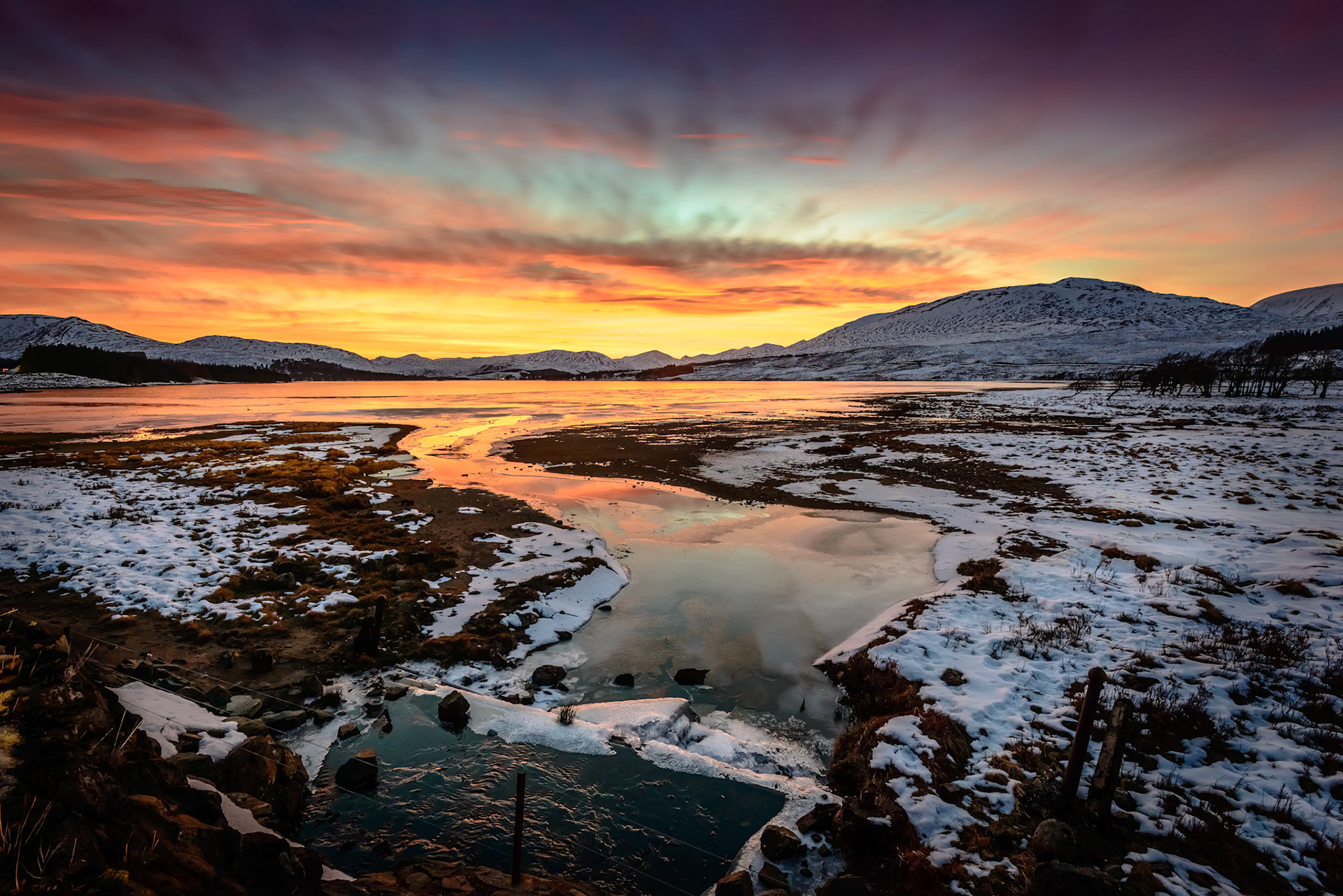 Twilight colours light up the sky over Lochan na h-Achlaise after the sun has set. Lochan na h-Achlaise is an irregular shaped freshwater loch on Rannoch Moor, Argyll and Bute in the Scottish West Highlands.