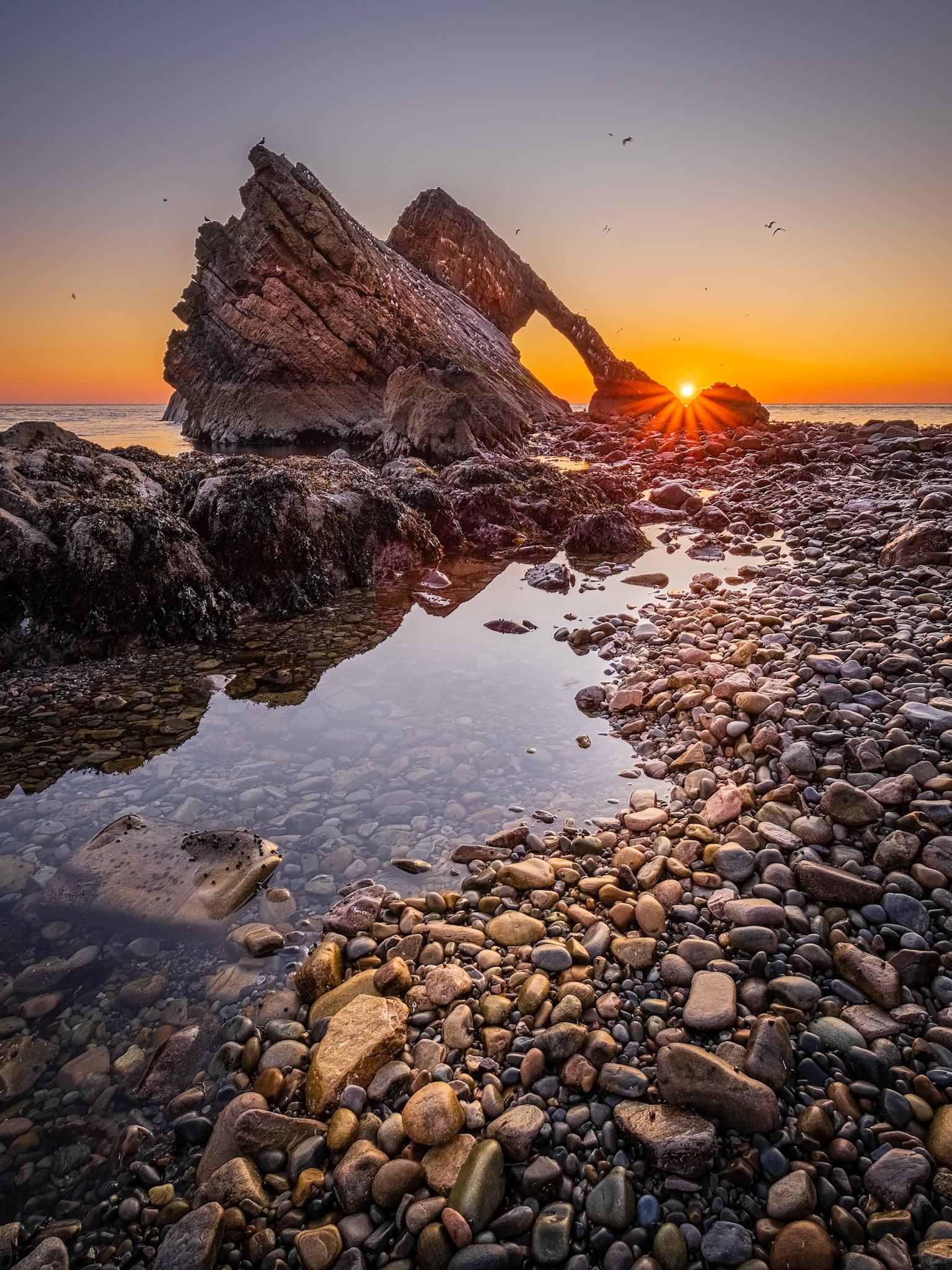 Sunrise above the Bow Fiddle Rock sea stack in Portknockie, Moray