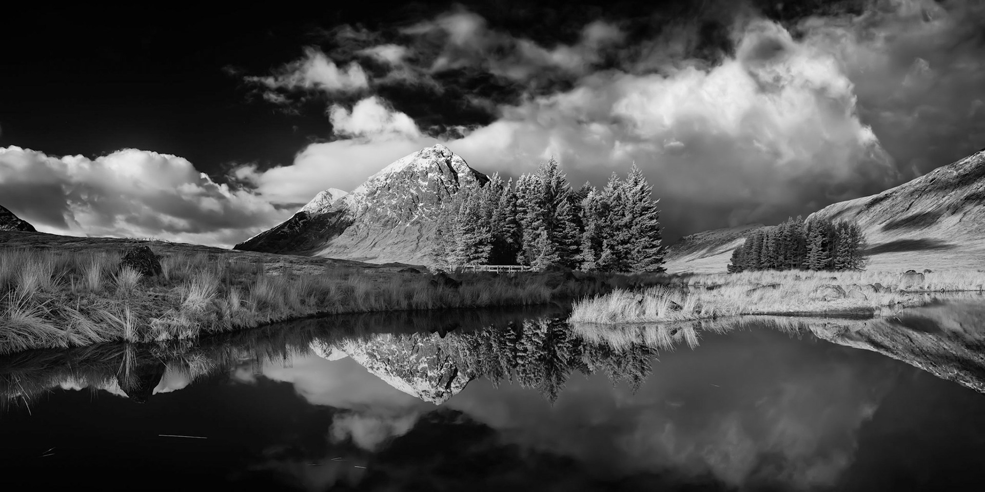 A black and white image of Buachaille Etive Mor in Glen Coe, Scotland, reflected in the pond at the Kingshouse Hotel