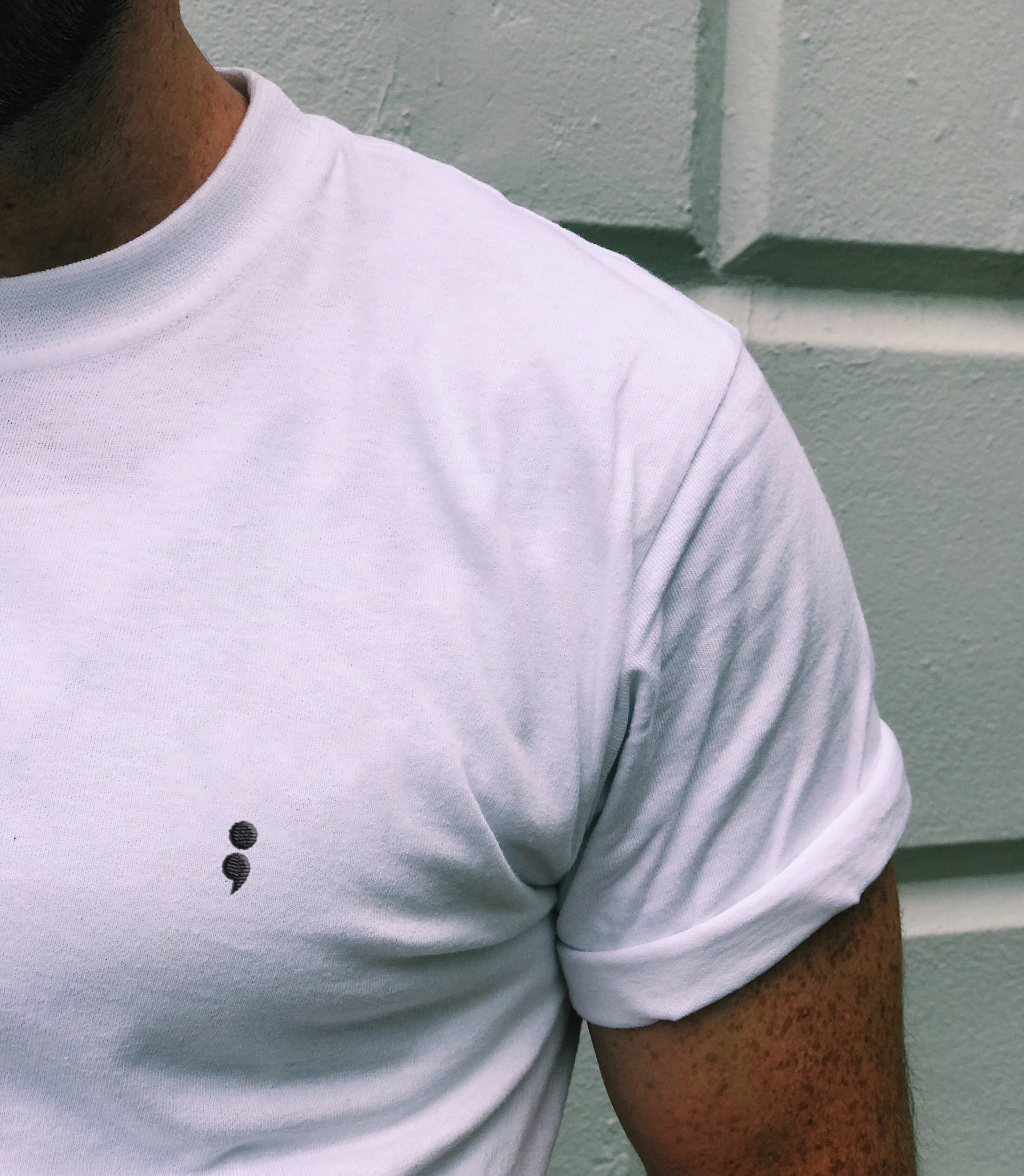 Man wearing a white t-shirt with embroidered brand symbol