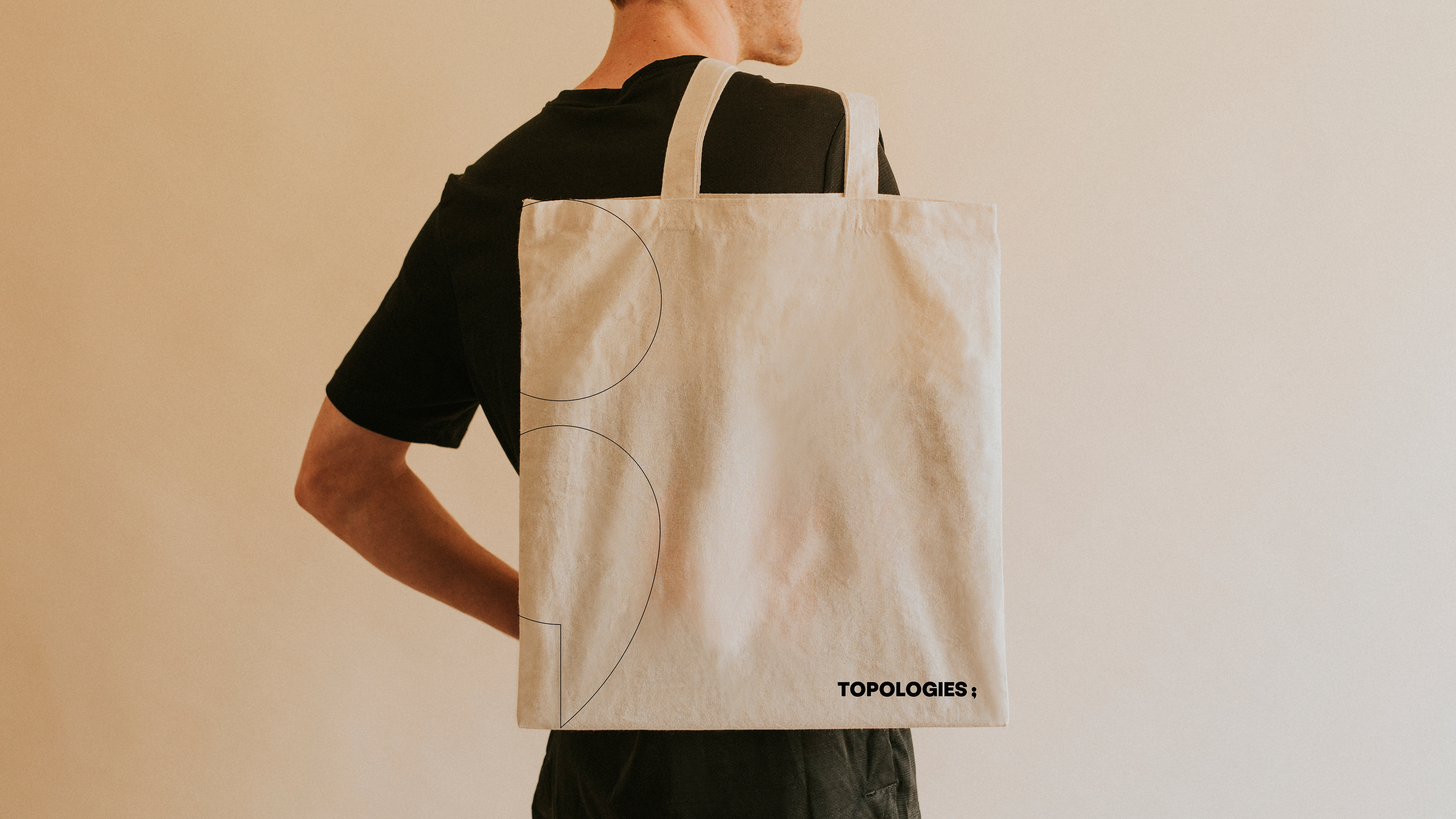 Man carrying a tote bag with Topologies logo and identity element