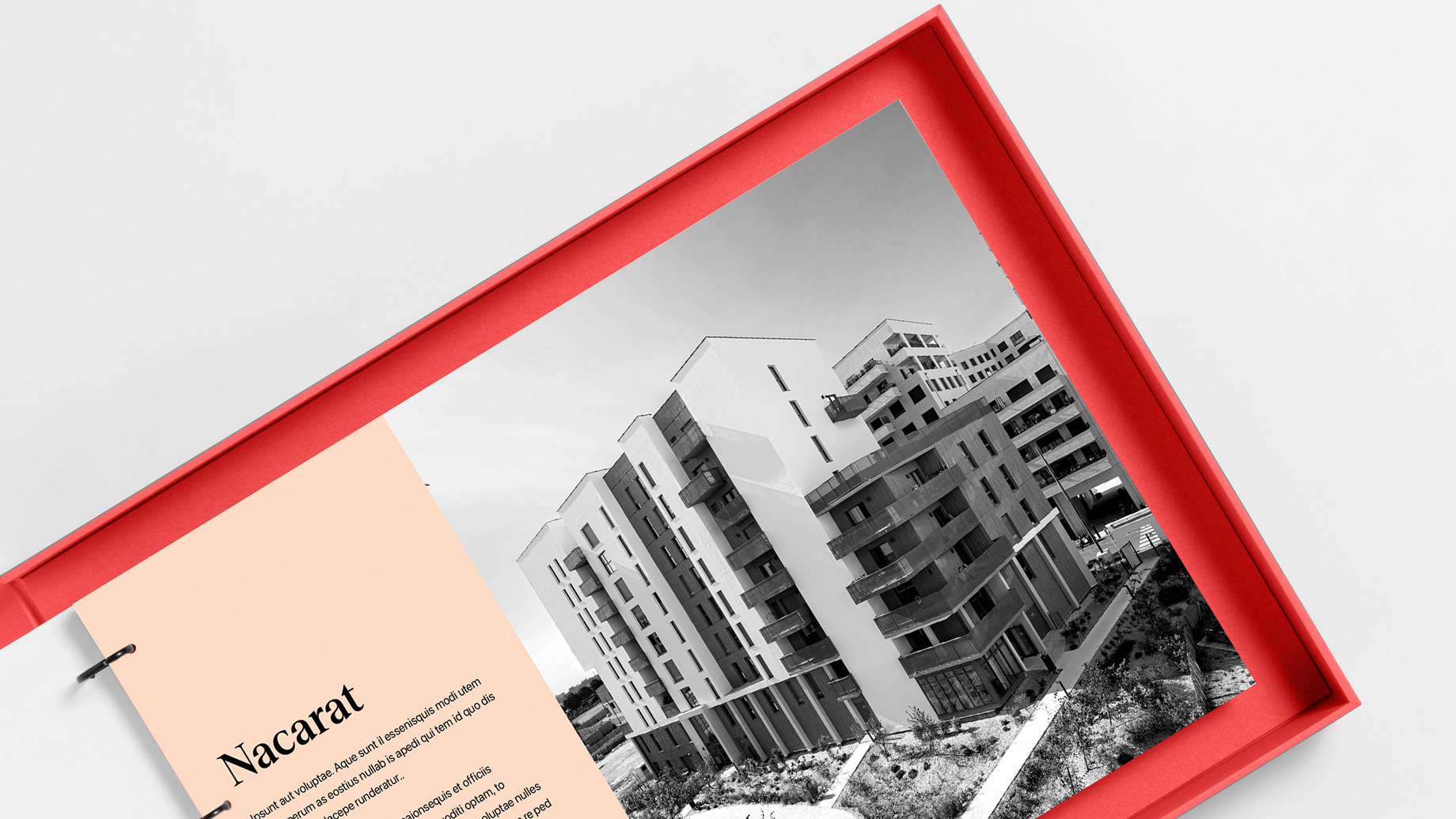 A red folder open to a page showing text with a black and white image of a building by Nacarat