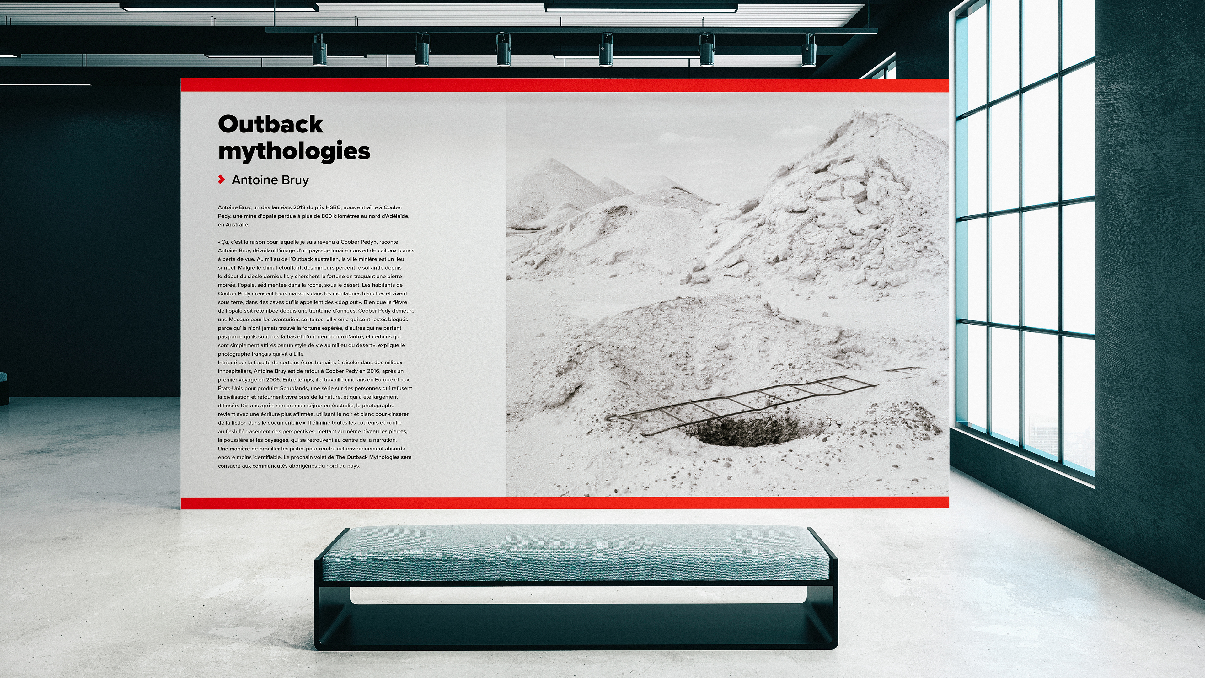 Exhibition wall with text, black and white image and red stripes in front of a bench in an exhibition room
