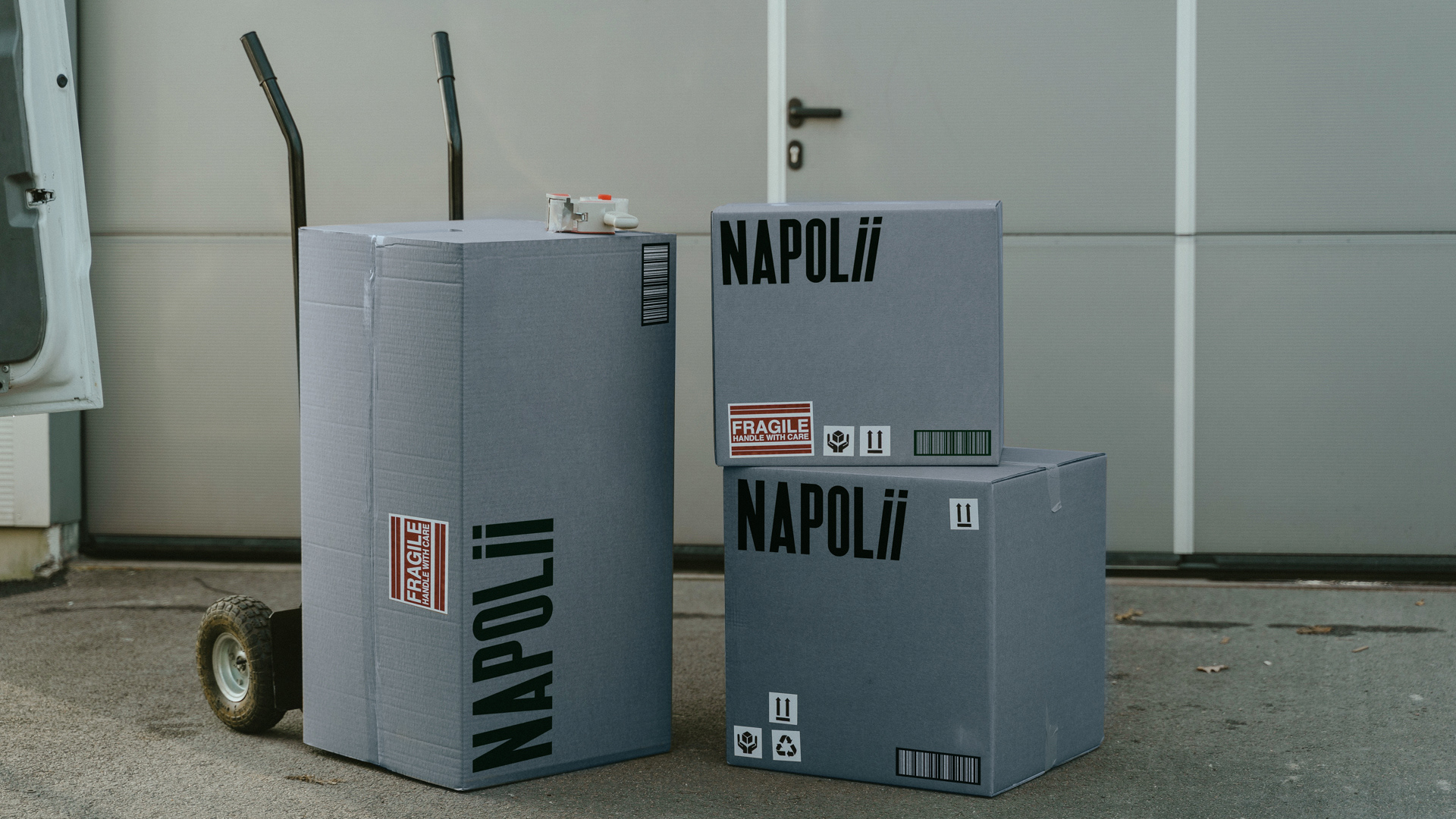 Blue cardboard boxes in front of a warehouse with stickers and Napolii logo