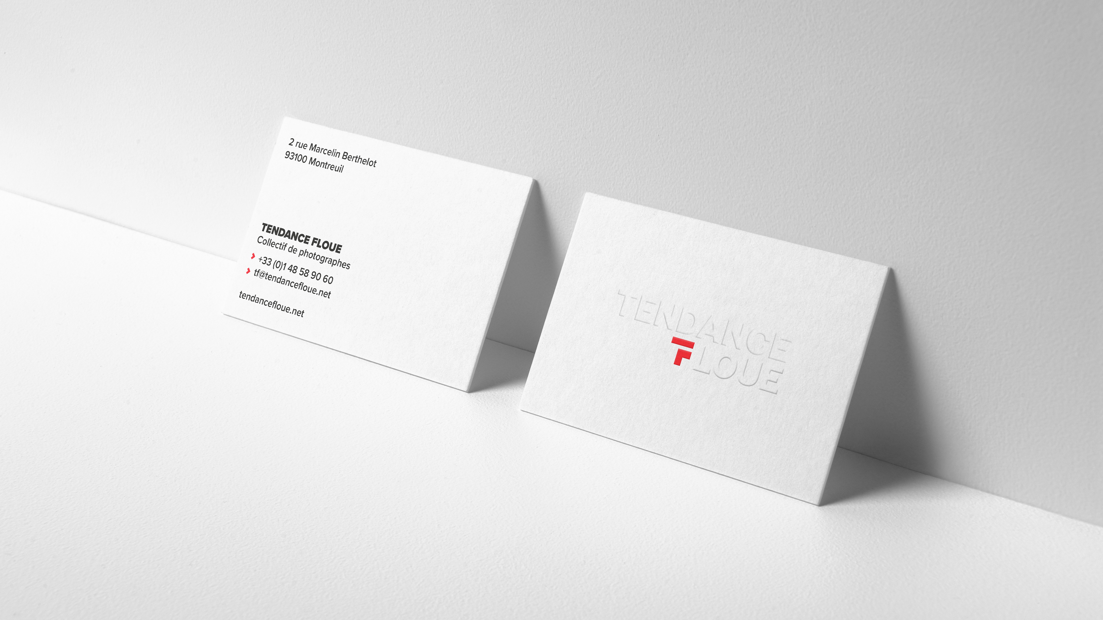 Front and back business cards with white embossed logo and red brand symbol and contact information