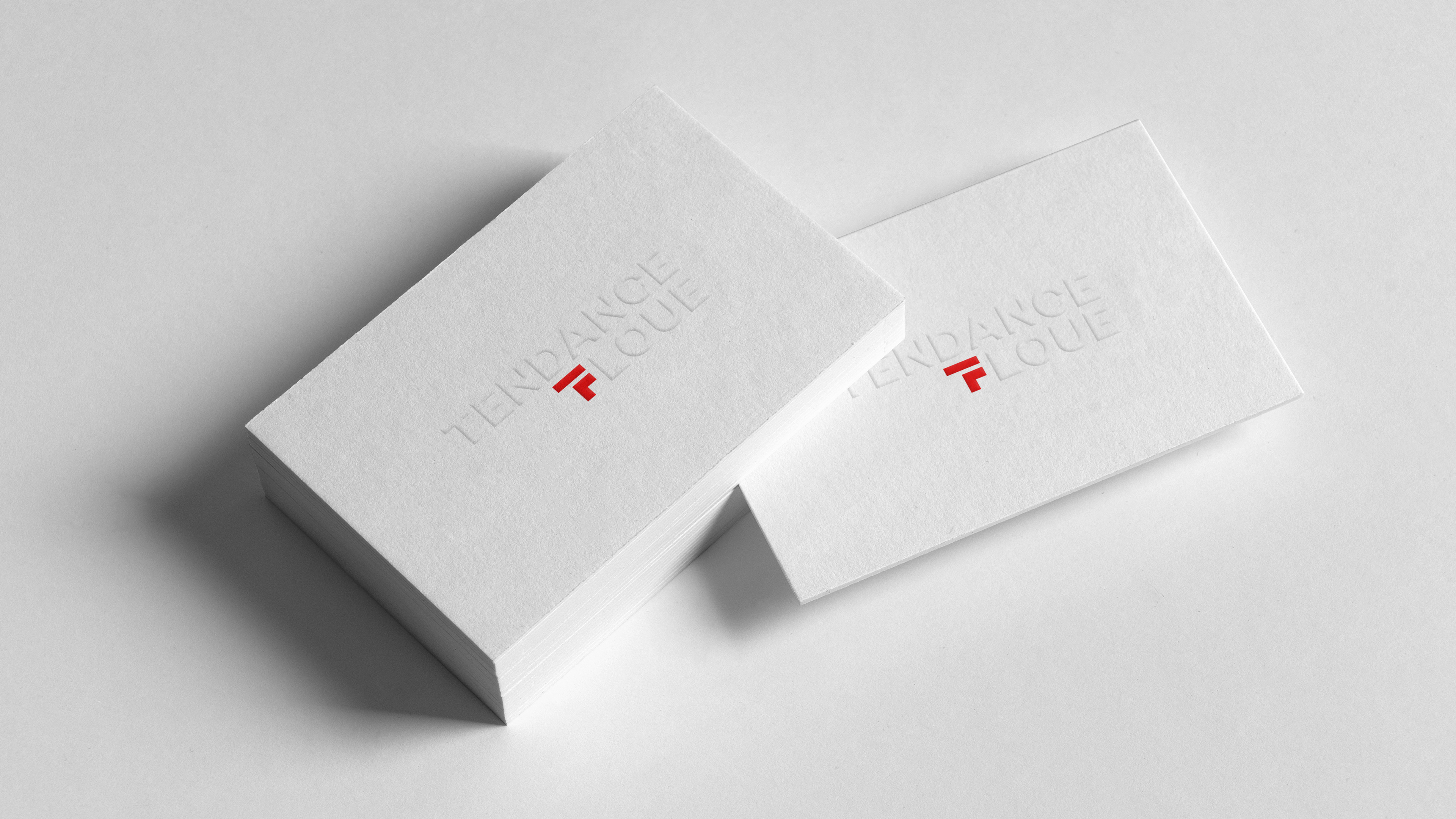 White business cards with white embossed logo and red brand symbol