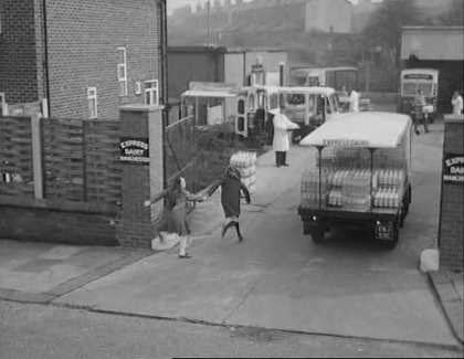 1965 film "Cup Fever". "Children from Barton United are trying to win the local league cup but a local Councillor does his best to ensure that his son’s team wins instead. Skipper and Rocket talk as they help deliver milk. (Naysmith Road in Eccles, with Roby Road and high rise blocks off Cawdor Street in the background.) Rocket delivers more notes advising of the location of the next match. (Shaftesbury Avenue in Eccles) The milkman is asked to help. (Parr Street at the entrance of Lewis Street School with the rear of properties on Renshaw Street forming the background.) A third milkman is asked to join the hunt. (Lewis Street in Eccles) The milkman drives Stopper to the ground. (Edison Road with Shakespeare Avenue to the left.) The floats come to a stand and the missing players rush towards the ground's entrance. (Golf Road with buildings on Moss Lane in the background.) From: https://www.reelstreets.com/films/cup-fever-childrens-film-foundation/