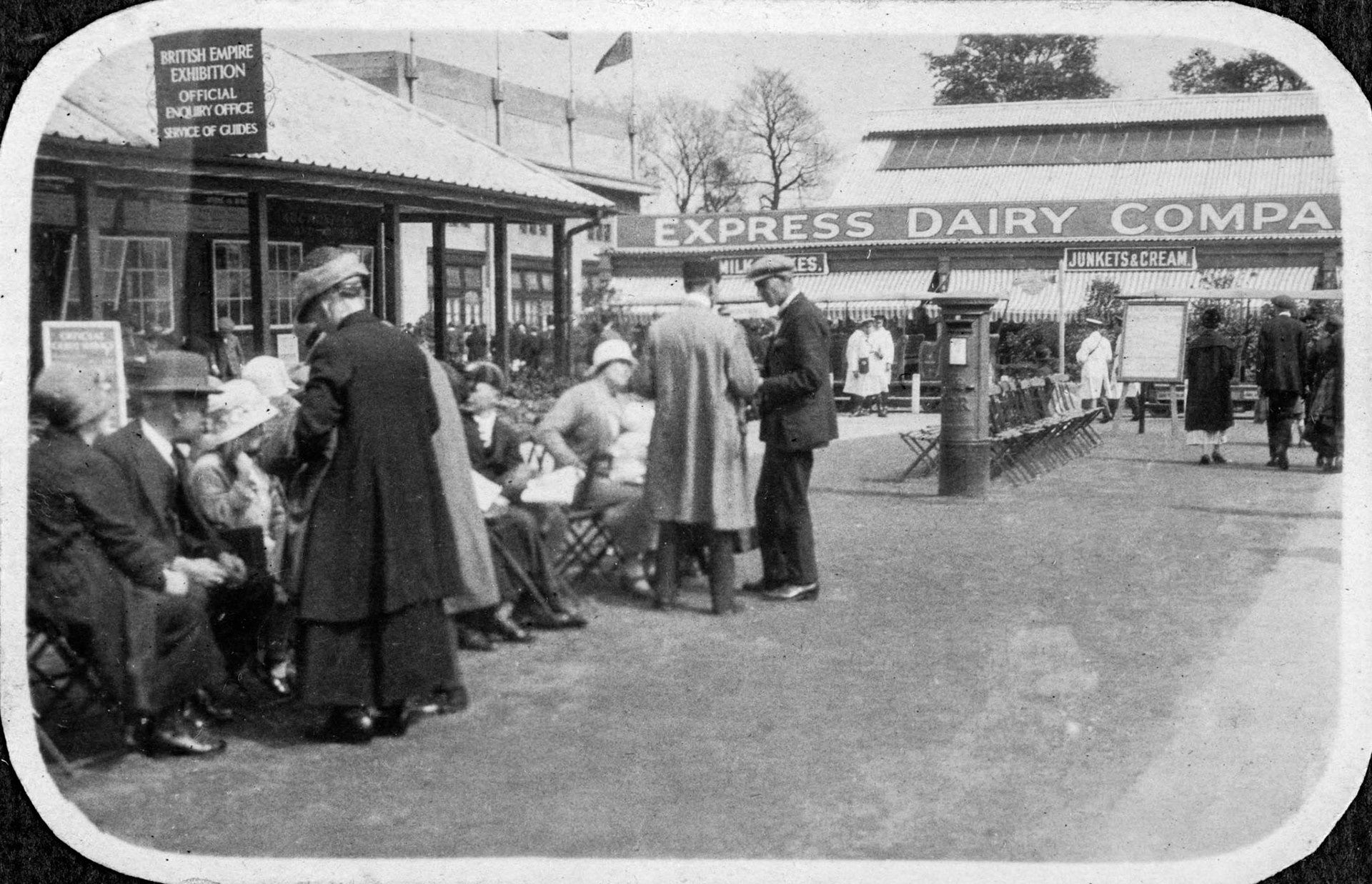 1924/5 British Empire Exhibition, Wembley Park, Brent, HA9. The handwritten caption reads: "This photograph shows a party of visitors, just seated in order to arrange the guessing competition, and the prompt appearance of the attendant." (Historic England Archive)