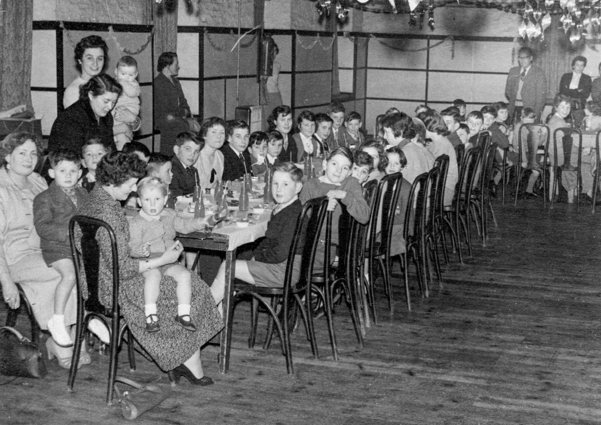 1958 Express Dairy, Frome, Christmas Party.. Dave Coleman comments "I’m sitting on Mum's lap with my brother Chris sitting next to us, I was two in 1958". Colin Carpenter comments "I'm pretty sure that Colin Hewitt is looking up from the table with his mum Ruth Hewitt just behind. Just behind Ruth is my mum Phyllis Carpenter with, I think, my brother Peter in his arms, who would have been 7 months old at the time. I think I'm sat next to Colin Hewitt with just my hair visible, aged 3 years and 10 months. Almost certainly taken at the old Welshmill Road site that was demolished in the 70's but had a real charm for those parties." (Courtesy James Parsons)