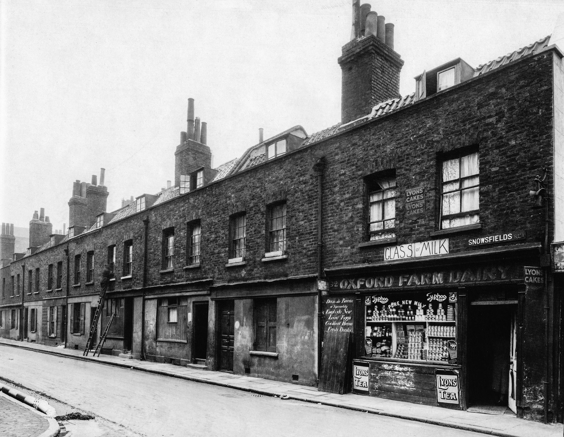 1943. 92-101 Snowsfields, Bermondsey, wartime view but could have been taken 50 years earlier. Little has changed - dingy, soot-blackened frontages and an air of world-weary decrepitude characterised many of London's poorest districts. Surprisingly for wartime, Oxford Farm Dairy is well-stocked with canned produce. (Courtesy GLC Historic Buildings Collection)