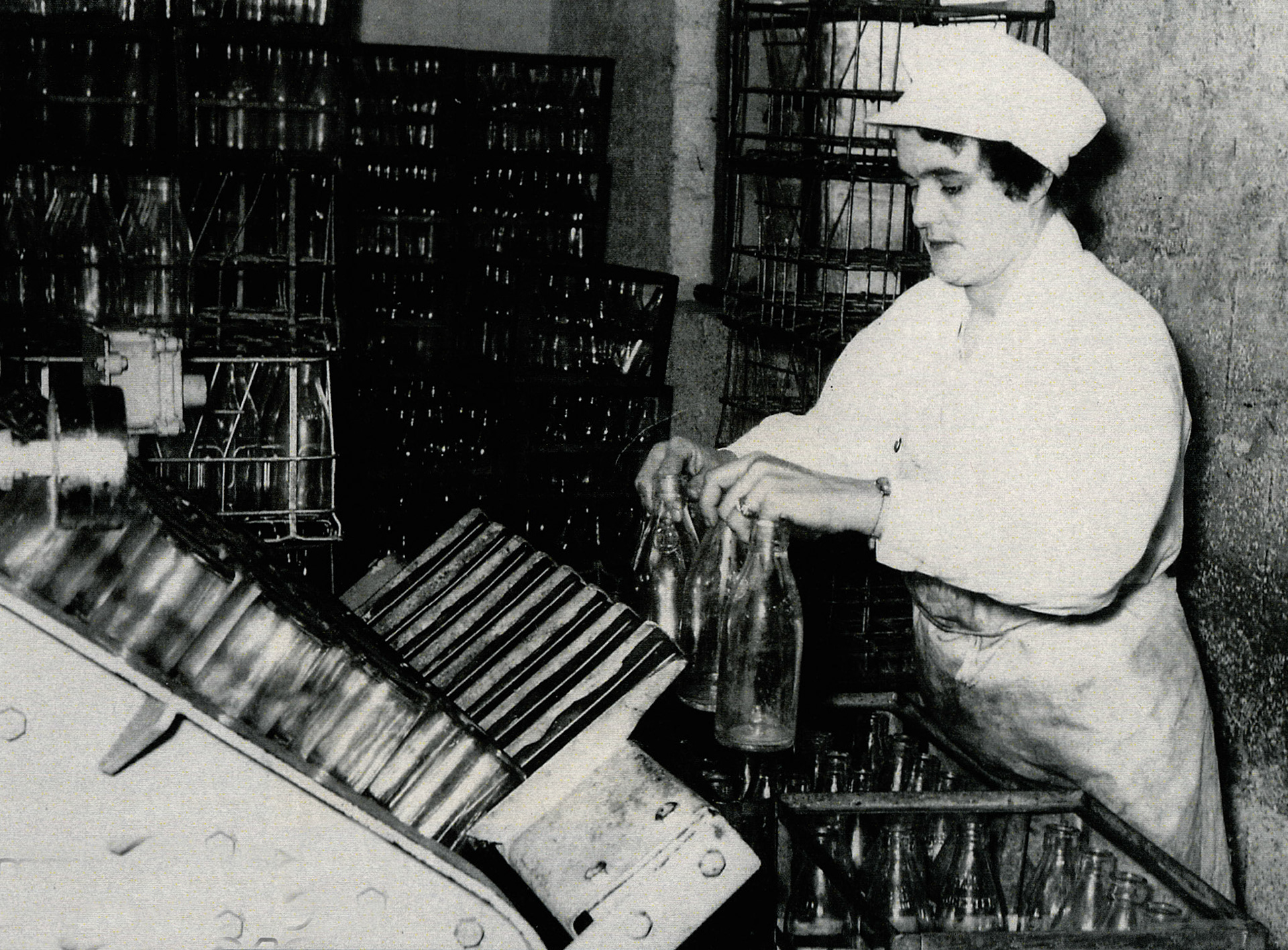 1957 Cotteswold Dairy - Min Danter feeding bottles into the bottle washer by hand. (Courtesy Dave Fane)