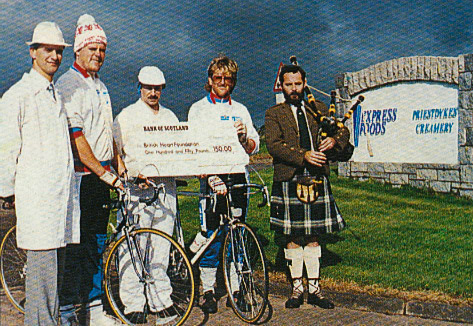 1989 Charity Bike Ride raises £7500, calling at Lockerbie, where Paul Fewings and Tim Eden collected a cheque from Jim Bell (Factory Manager), Jim Bell (Social Club Chair), Allen Patterson (local teacher) and James Rae (bagpipes)