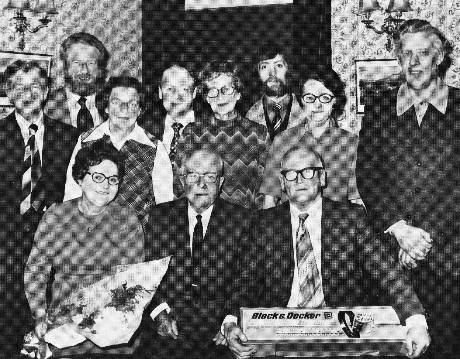 1977 Herbert Simms chalked up 51 years' service. Seen here, clutching an electric hedge trimmer, he joined us on leaving school and remained a pillar of our Bradford Model Dairy from first to last. As a dairy hand and driver he earned the friendship and respect of his colleagues who stood him a slap-up feast at 'The Shoulder of Mutton', Batley Carr. Mrs Simms was presented with a bouquet and the Company came across with a cheque. (Express News Autumn)