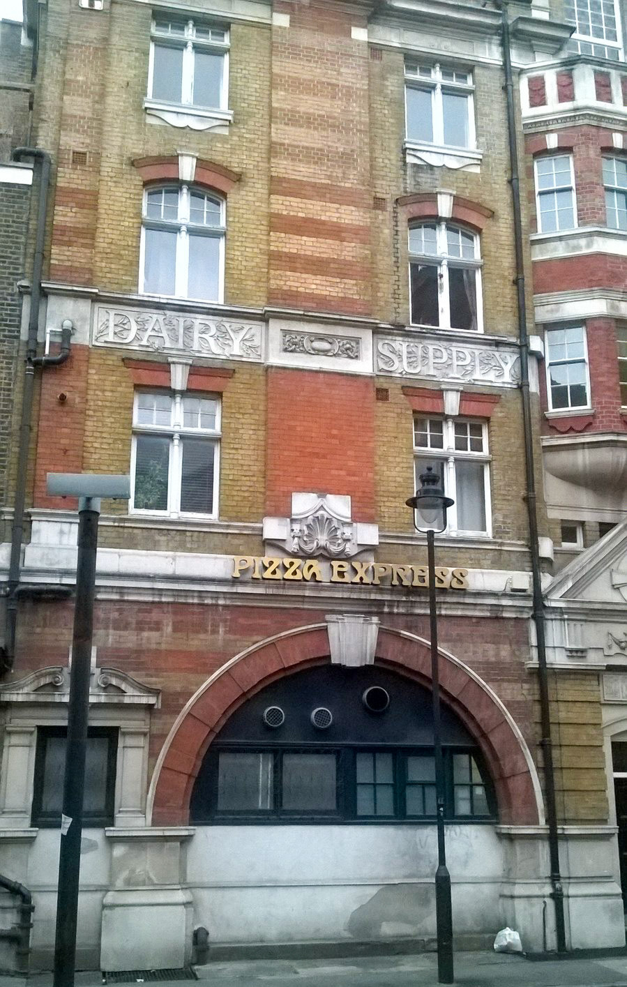 Dairy Supply Company (now Pizza Express) Architect: R.P. Wheelock. 1888. Location: 30 Coptic Street and Little Russell Street, WC1. Courtesy(Photographs and caption by Robert Freidus. Formatting and perspective correction by George P. Landow https://victorianweb.org/sculpture/architectural/92.html)