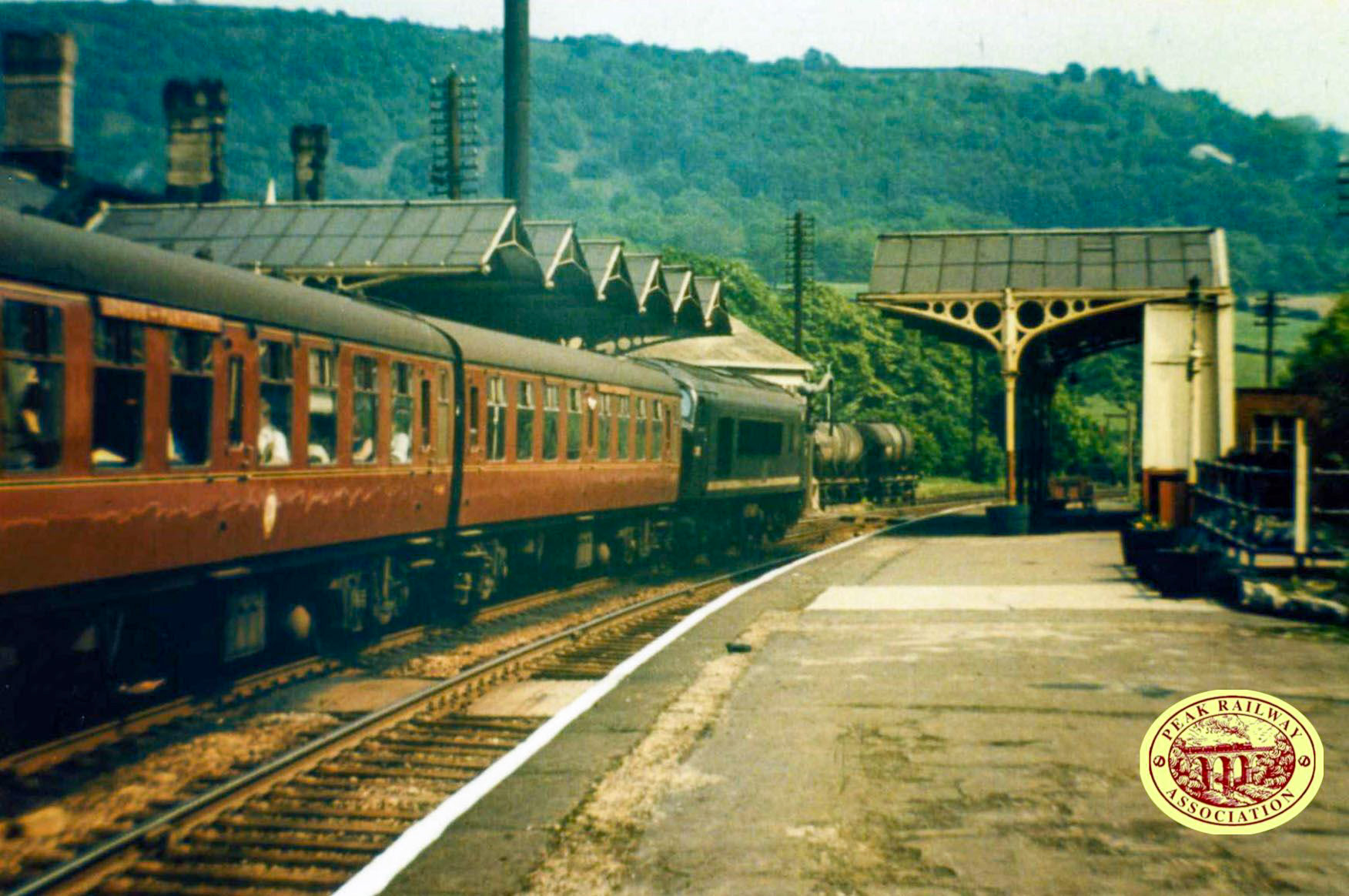 1950s? Rowsley station looking towards Matlock. Peak Rail comments "The late Arthur Dudson made a very significant contribution to the development of Peak Rail with a lot of detailed plans which were used to rebuild the track in various places on the route. Just look at the period atmosphere it contains; a Peak on an up express, coaches with roof boards to show the route of the train and also a couple of milk tank wagons in the dairy siding at the end of the platform." (Courtesy Peak Rail Archive)