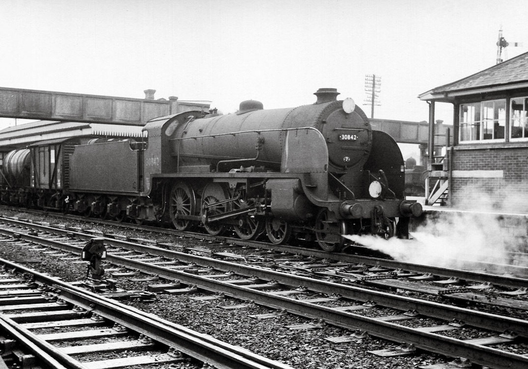 1963 Seaton Junction, from Cornwall Railway Society - "S15 30842 stands by the signalbox with an interesting train and waits at the down platform. An extremely long footbridge carries a public footpath not only over the four track main line at this location but also over the branch platform. Looking between the front of 30842 and the signalbox the Seaton branch engine, on this occasion 6412, stands at the branch platform. 11th September 1963 Copyright Mike Roach."