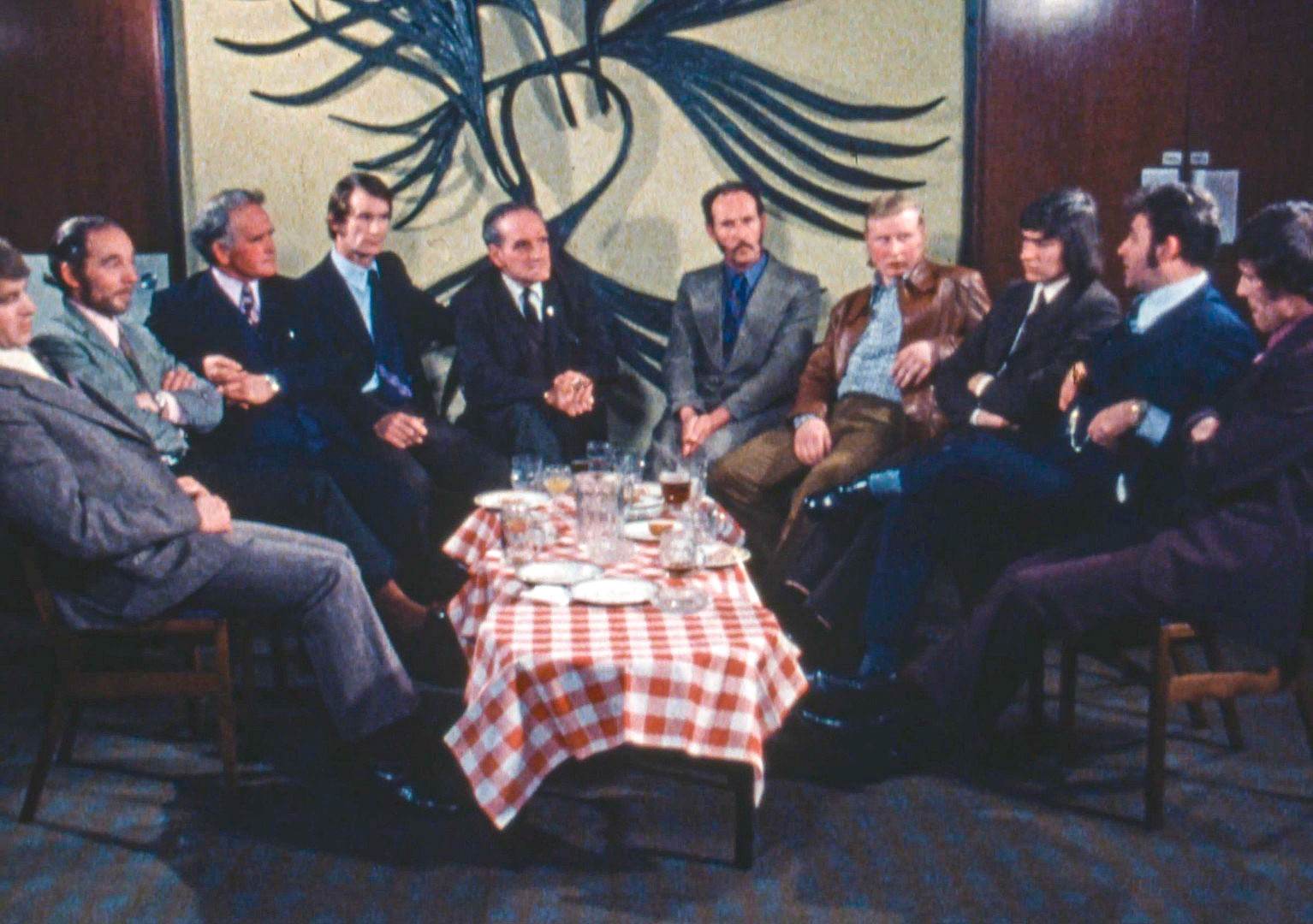 1970s ‘Milkmen's Discussion Group’ appears to be filmed in a hotel, with an unknown host asking questions and leading the discussion. Believed to be used at Robarts House training centre. Glyn Williams identifies Derek Dougan in the middle, grey suit. (Still from video)