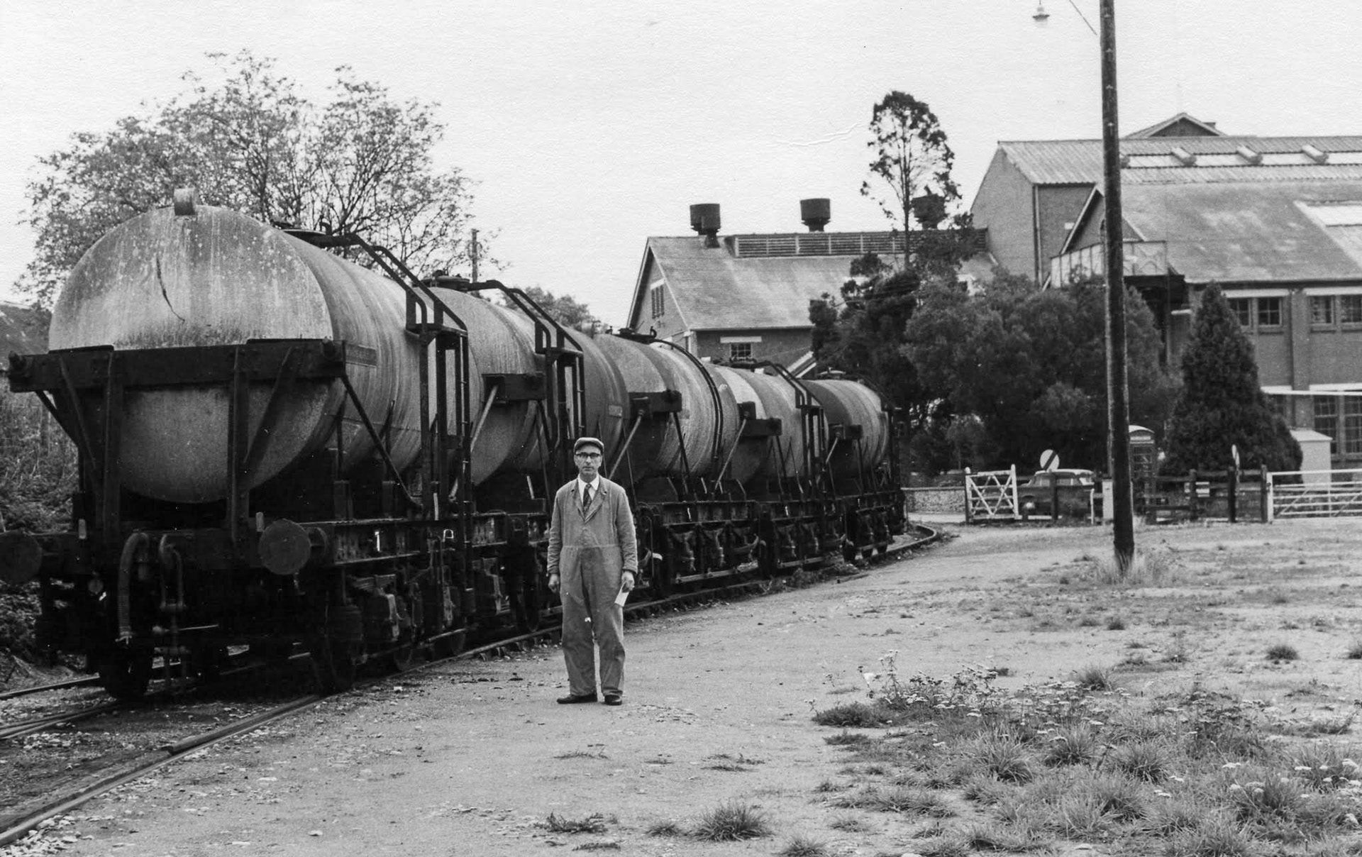 1960s? Hemyock, Devon-"A rake of milk tanks on the northernmost siding that crosses the road and enters the dairy." Amyas Crump and Mike Pike recognise Len Mutter. Express only did egg packing at Hemyock, the dairy later became St Ivel. (Courtesy Discovering Devon, Somerset and beyond FB)