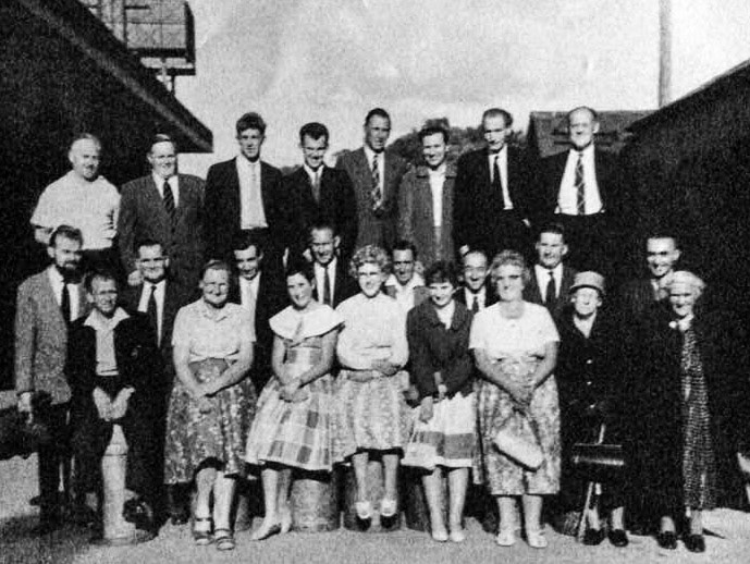 1954 Crediton. Posted by Jacky Phillips, comment by Jimmy Wills: "I put the photo on originally, it was loaned to me by Les Rich, just guessing 1954 or sometime around that time. I came on the milk lorries 1968 and a good many were still working there."Jacky Phillips: "Lady front row right is Mrs Heal, with her son Les behind (who lived in Newcombes Lodge)", Kym Moore: "Bill Tucker back row far right", Richard Adams: "Fifth from left, back row is Jim Broom", Tracey Clarke: "I do think that's my Dad Mike Sanders, top row, third from the left", Jimmy Wills: "Second in from the left, top-Denny Dance (Tubby), Third middle from the right-Ernie Bennett (Coco), front row left, sat on a churn-Eric Eastman", Terry Phillips: "My father Fred Phillips, fourth left, middle row".
