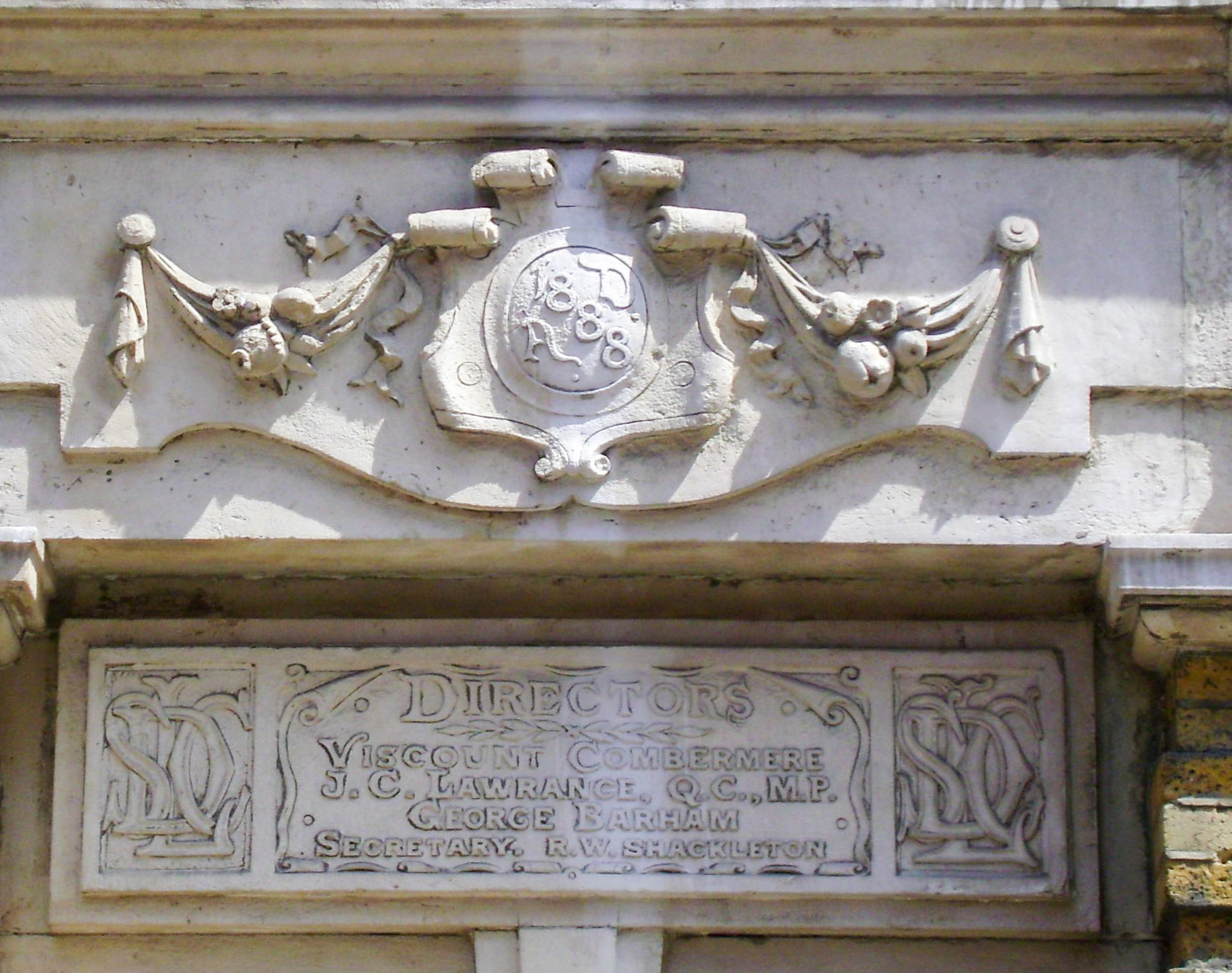 The Dairy Supply Company, Coptic Street. Inscription, above a door, on a cartouche:AD 1888, on the plaque below: Directors: Viscount Combermere, J. C. Lawrance, QC, MP, George Barham, Secretary R. W. Shackleton, and a monogram: DSCL. (Courtesy Baldwin Hamey, https://baldwinhamey.wordpress.com/2013/08/05/dairy-supply-company/)