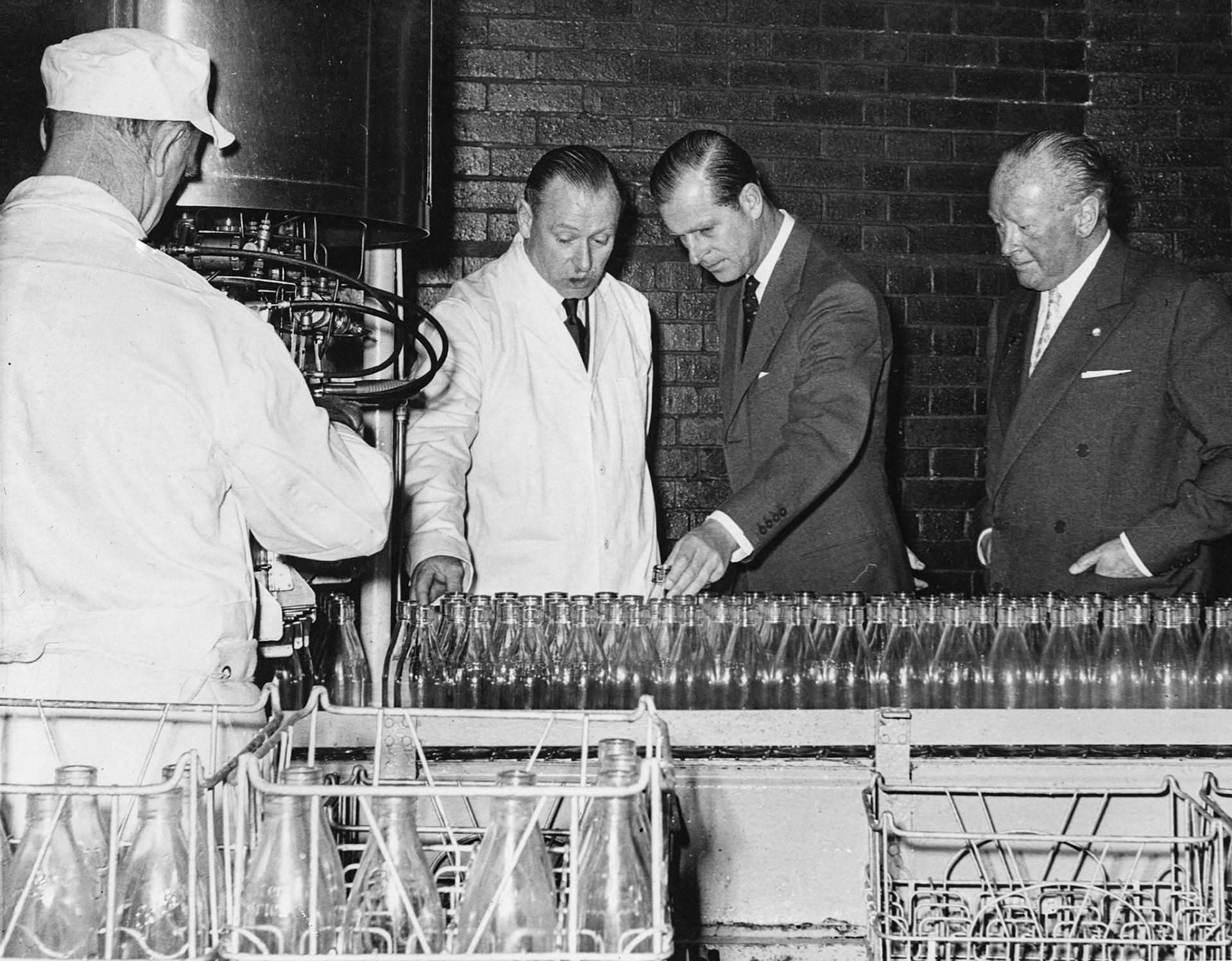 1957 South Morden-Duke of Edinburgh's visit on November 12-Mr L.W. McNair explains the  clean bottles entering the filling machine. (Courtesy Paul Luke)