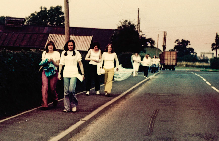 1972-3  Ann Worrall identifies Josie Purslow and Ann Robets in front, Jane Royal &amp; Maureen behind? "We did a 20m sponsored walk for Leukaemia after work." Jo Betts comments "I didn't even recognize myself! The jeans were pink denim flares not red as they look in the pic so it threw me a bit. Think I was about 21.".Matthew Taylor adds "I remember the old buildings on the left. Used to get wooden boxes to make go-cart seats from there. I think it used to be the the old egg packing and dairy."