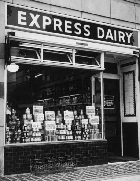 1960's Canons Park, Edgware HA8 Express Dairy shop window display, with a range of food including McVities digestive biscuits, processed peas and sliced peaches. (Courtesy Mary Evans Picture Library)